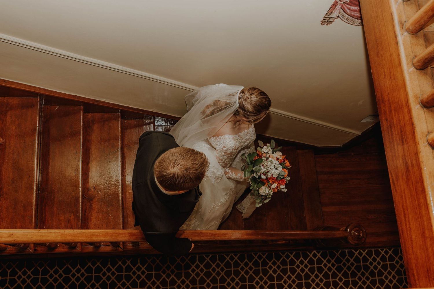 A couple pauses on wooden stairs during their wedding celebration.
