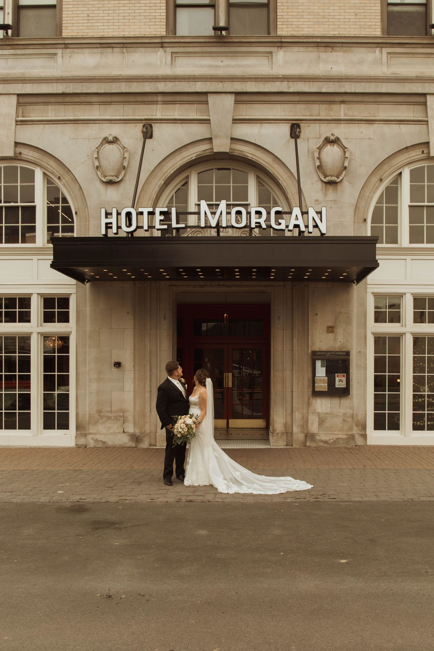 An elegant wedding portrait showcasing the classic architecture of Hotel Morgan's entrance.