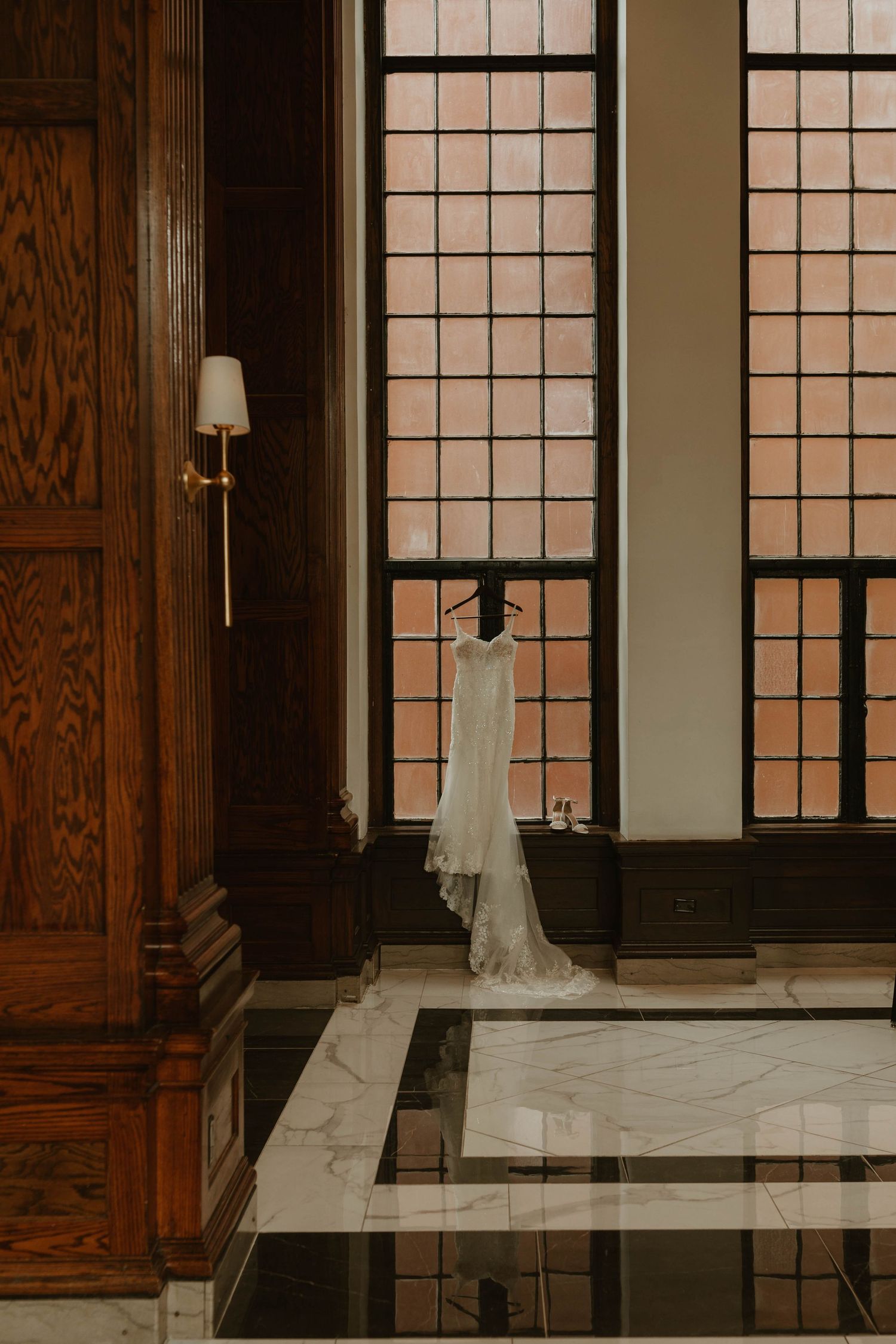 Interior of elegant venue with hanging white dress and marble floors.