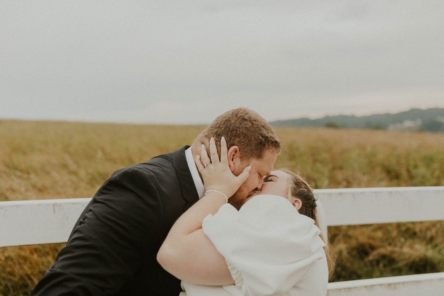 An intimate moment shared between newlyweds against a rustic fence backdrop.