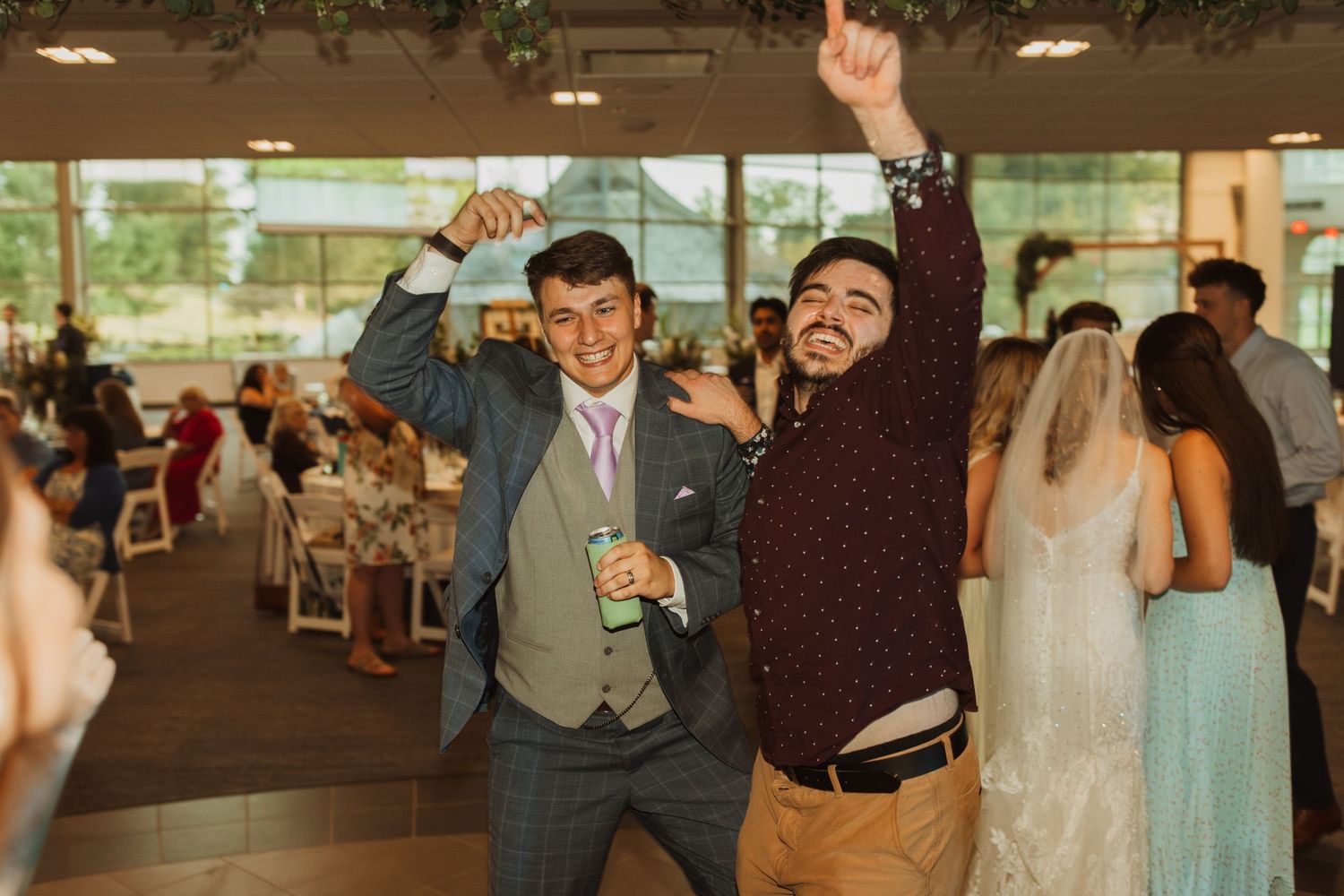 Wedding guests dance and celebrate enthusiastically at indoor reception venue.