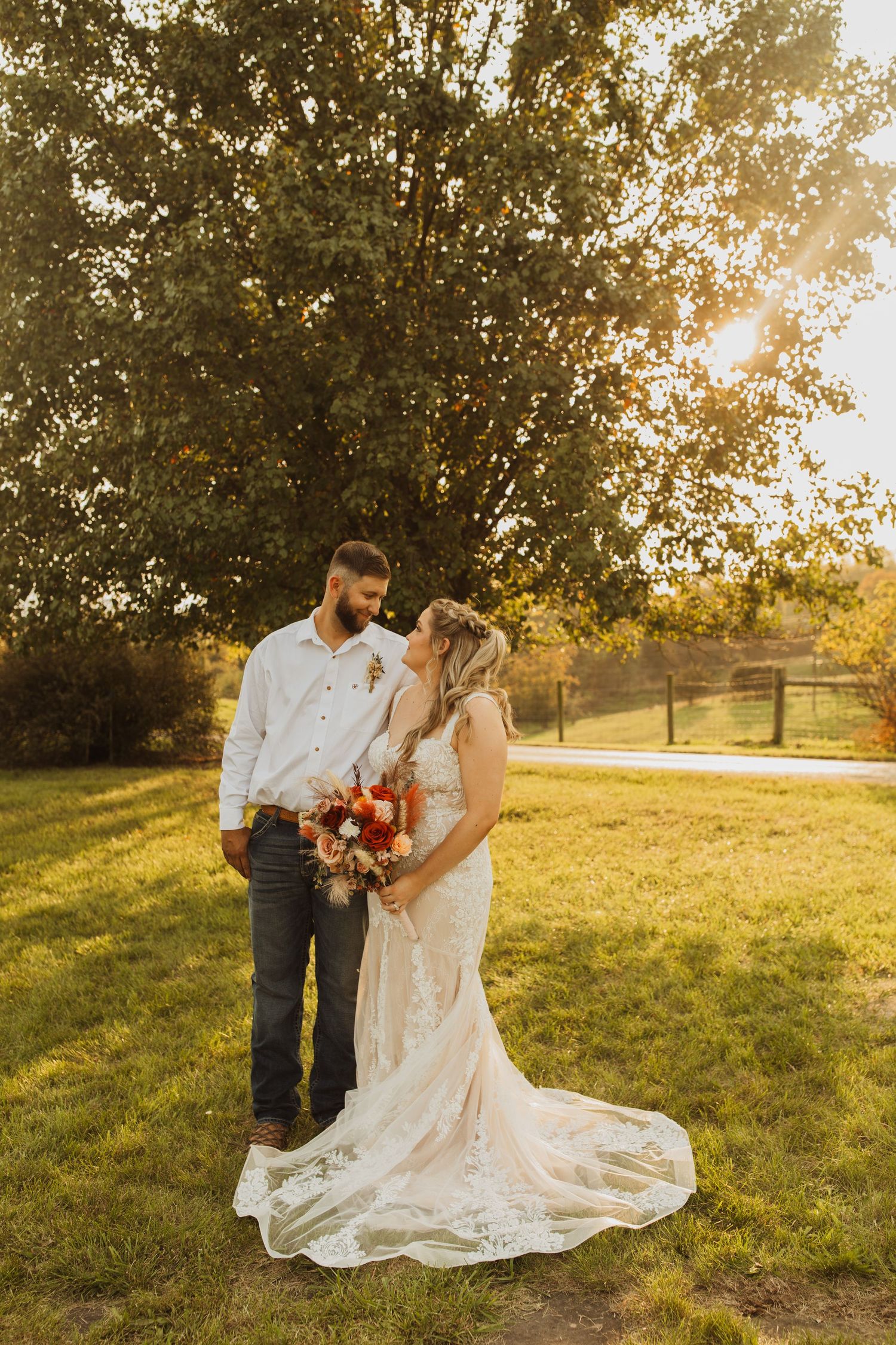 A couple shares an intimate moment at sunset in a field with autumn-colored flowers.
