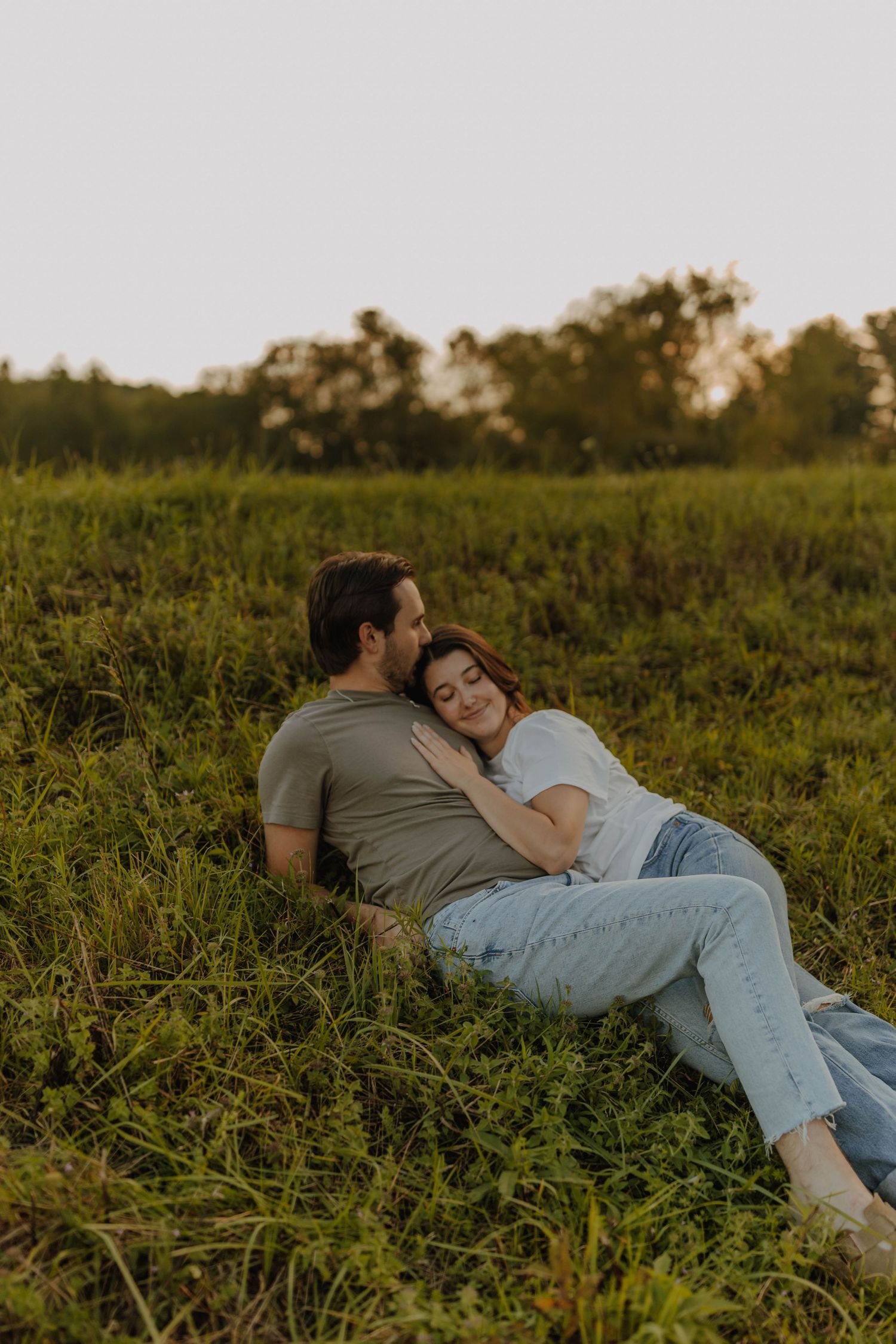 Couple relaxing together in a grassy field during golden hour.