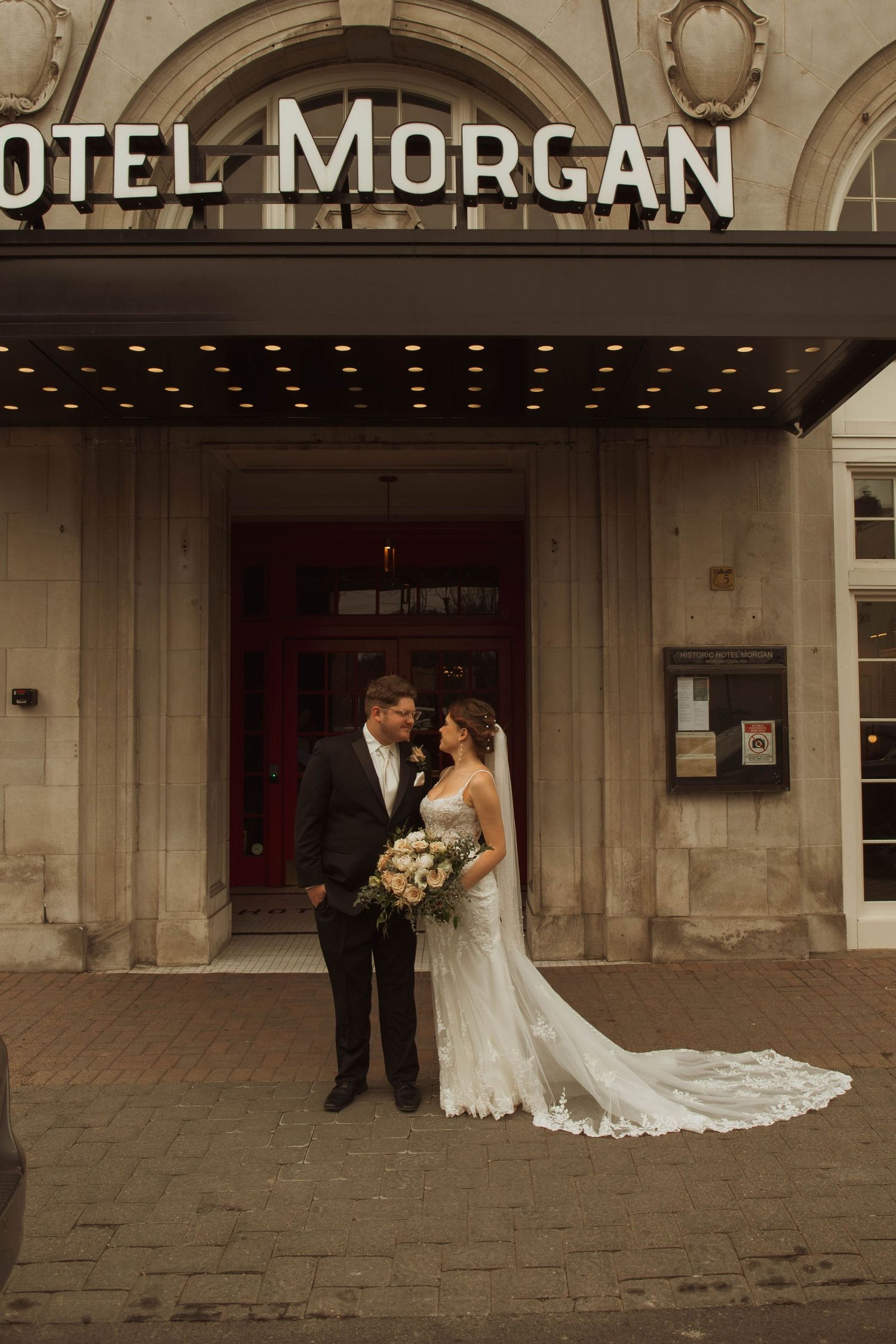 Wedding couple poses outside historic Hotel Morgan entrance.