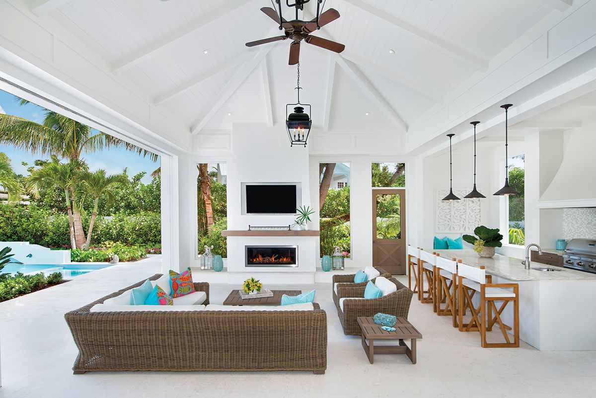 Luxury outdoor living space with vaulted ceiling, TV, and comfortable seating overlooking tropical garden.