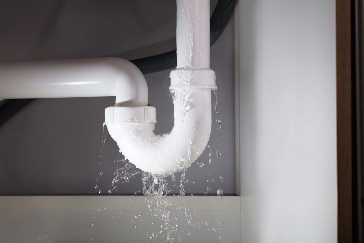 White PVC pipe joint leaking water from connection point.