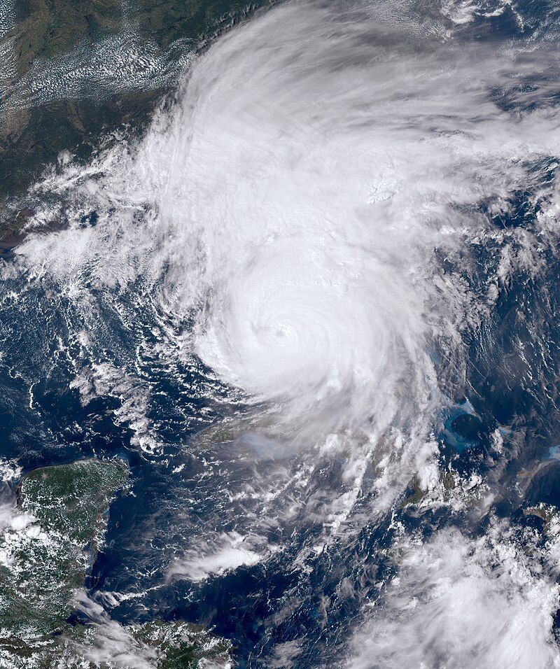 Satellite view of a large tropical cyclone with a distinct eye swirling over the Atlantic Ocean near coastal land masses.