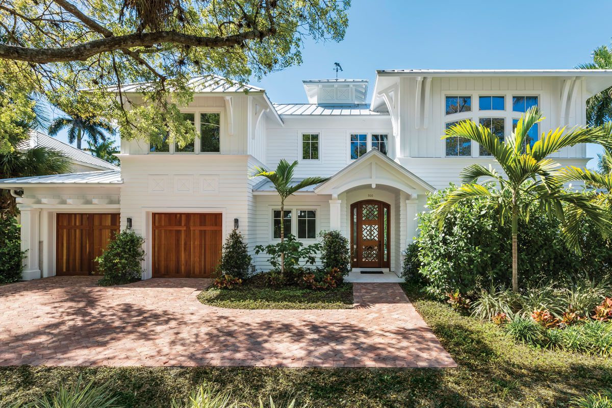 Elegant white Mediterranean style home with palm trees and landscaped front yard.