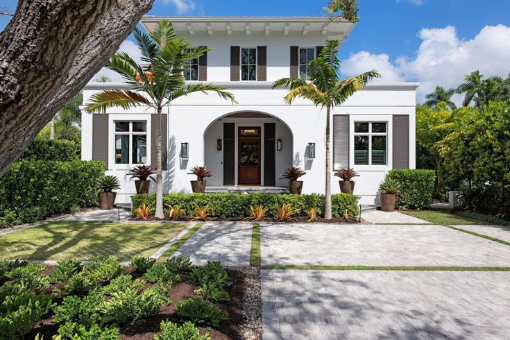 White Mediterranean villa with arched entrance and manicured tropical landscaping.