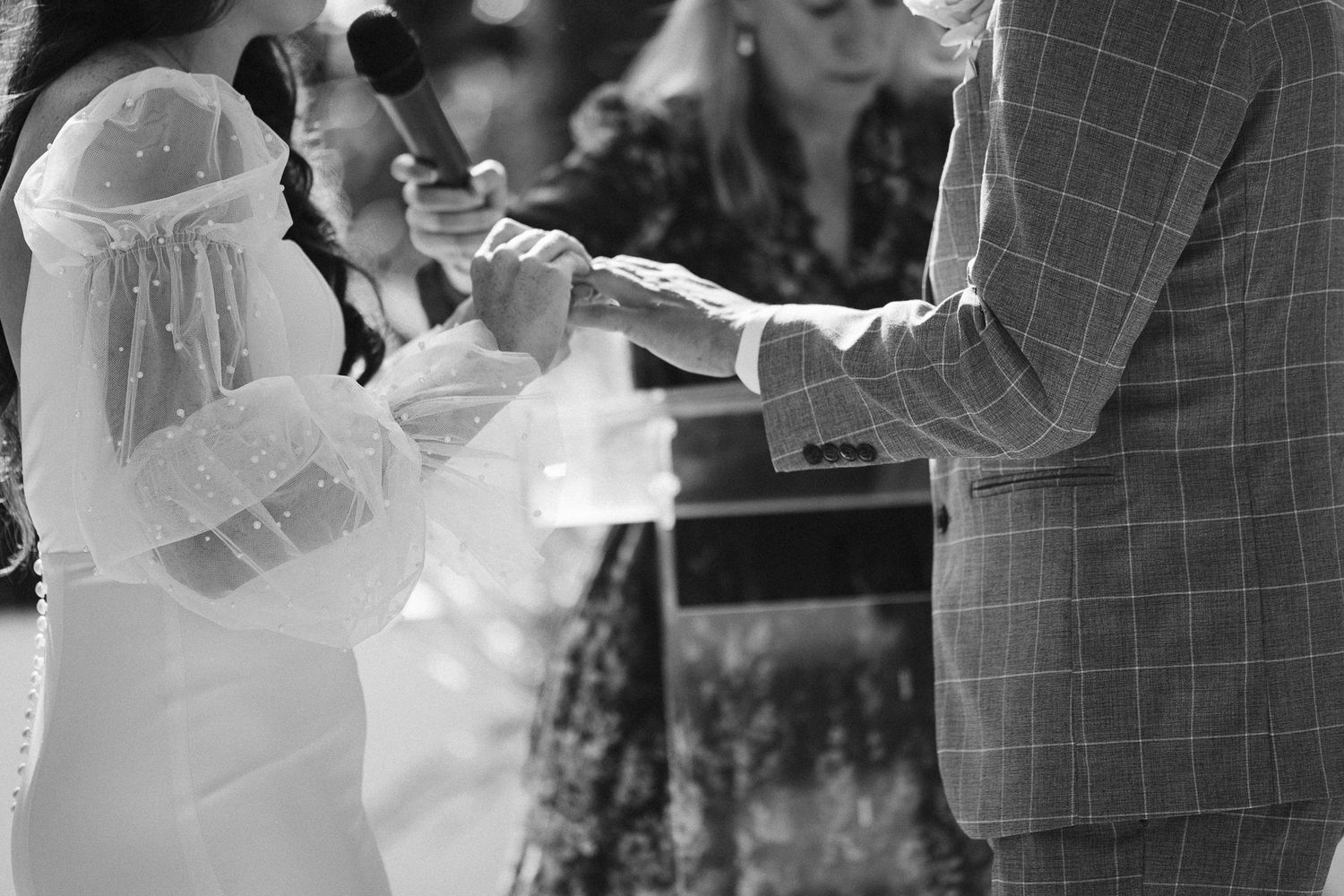 Black and white photo of bride and groom exchanging vows during an outdoor wedding ceremony.