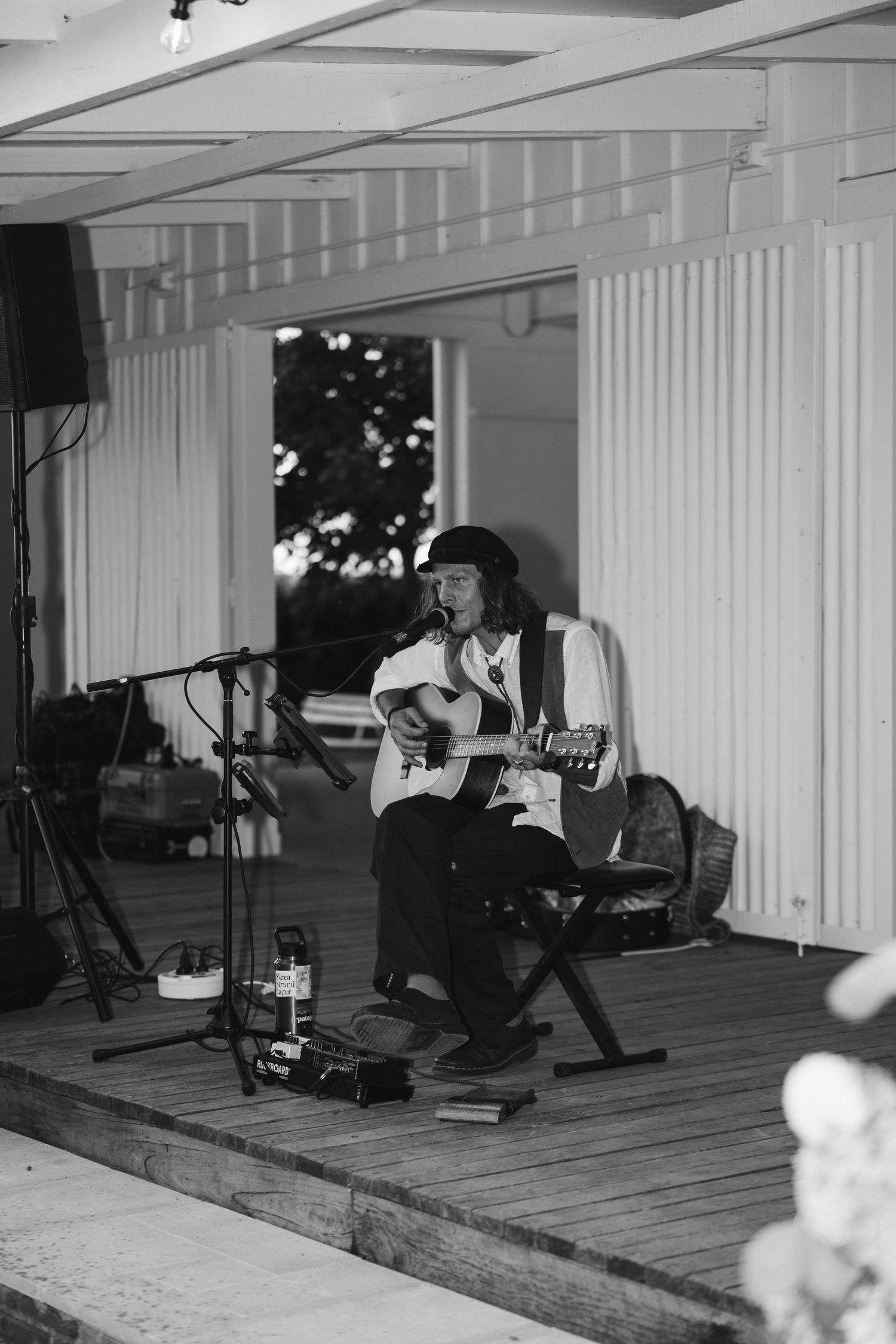 A musician performs on acoustic guitar on a wooden stage with professional audio equipment.