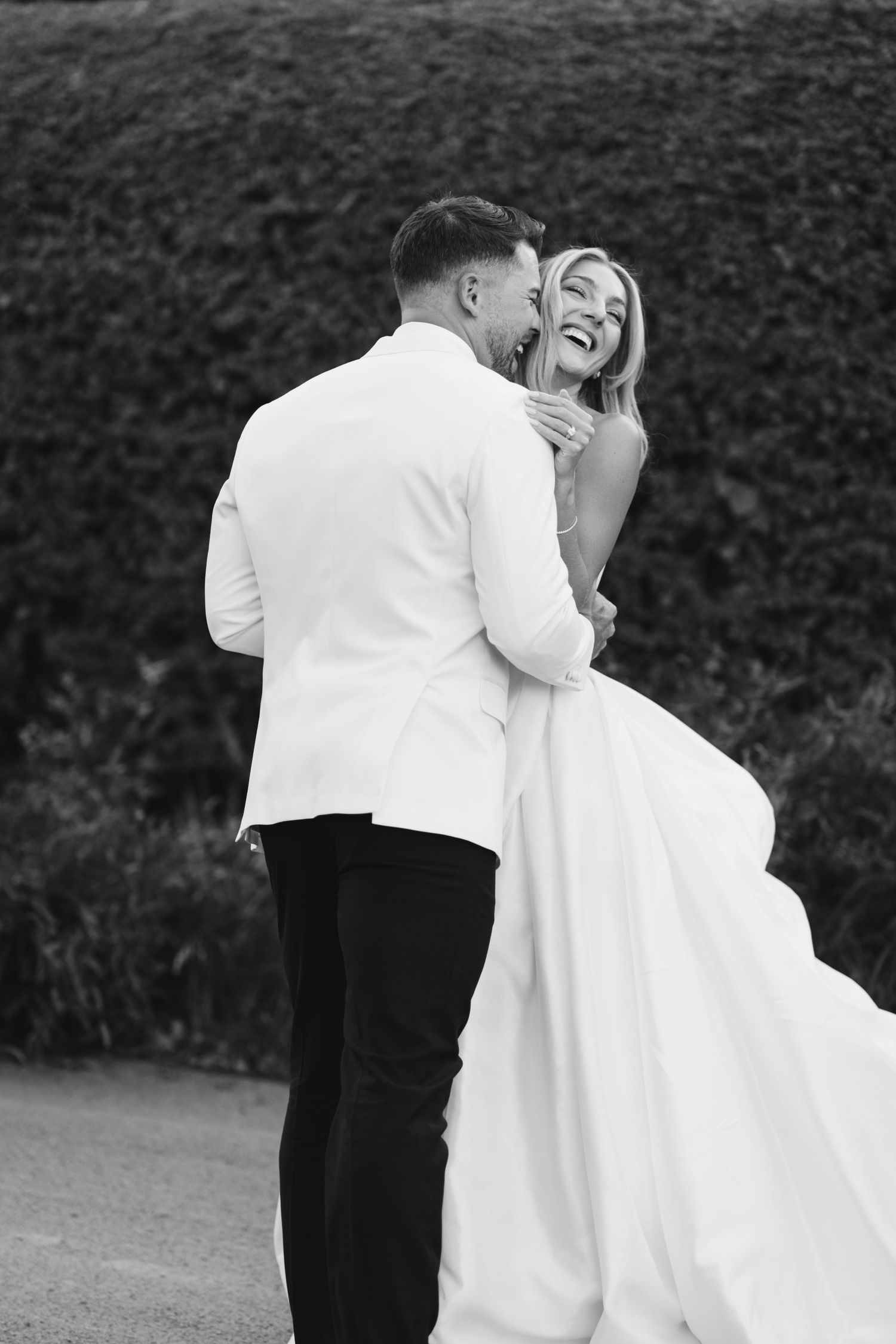 Black and white photo of laughing couple in intimate wedding moment.