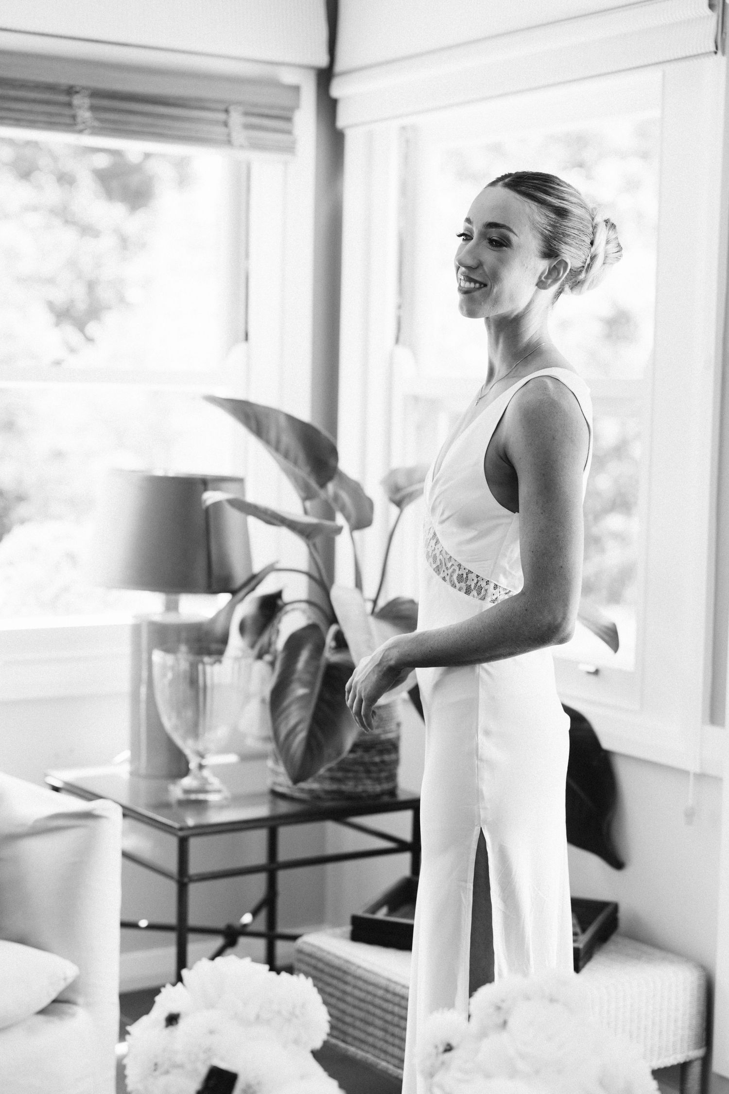 A joyful moment captured in black and white as someone wearing a white dress stands in a sunlit room.