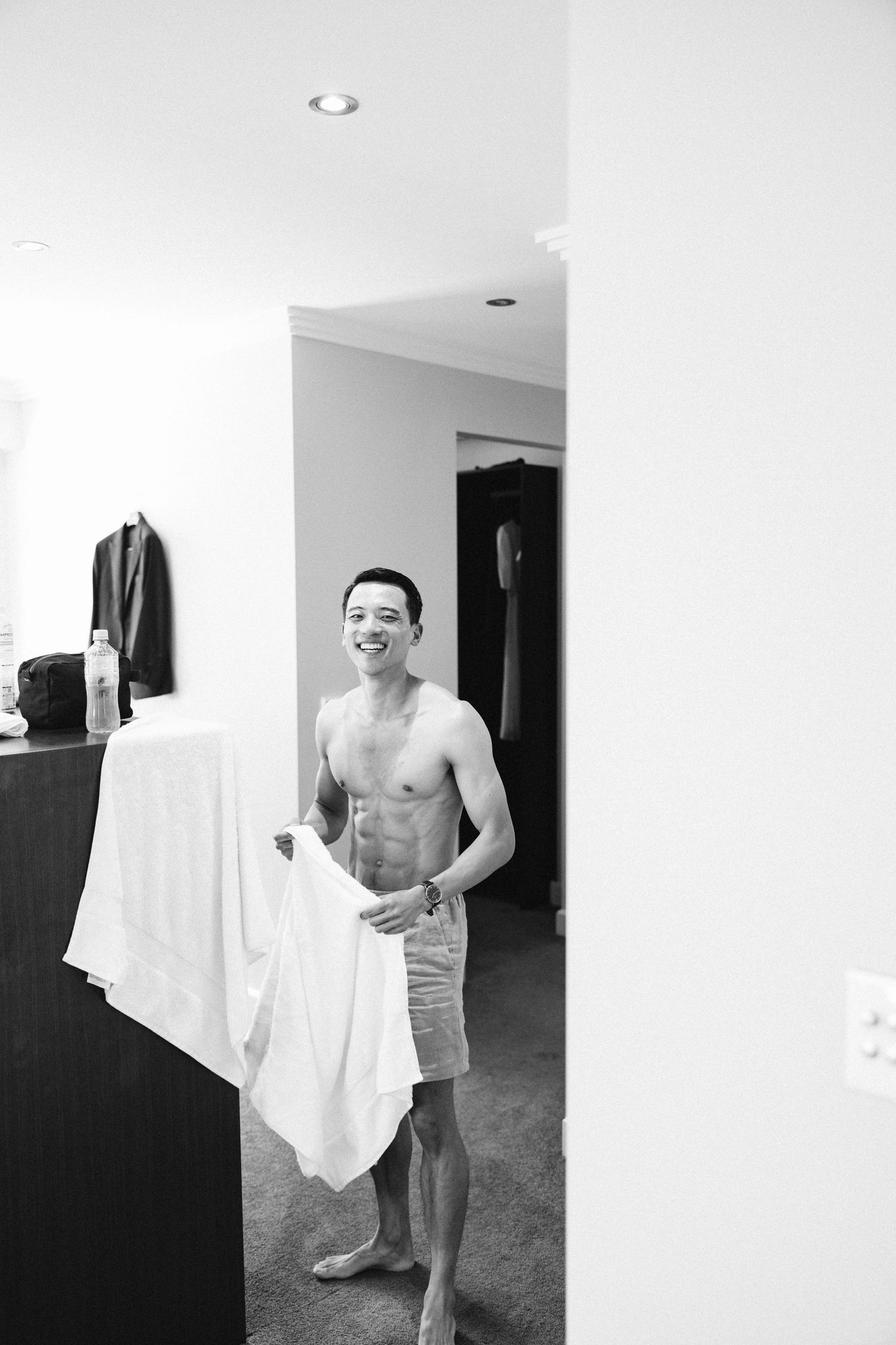 Black and white candid photograph of wedding day morning preparations in a bright room.