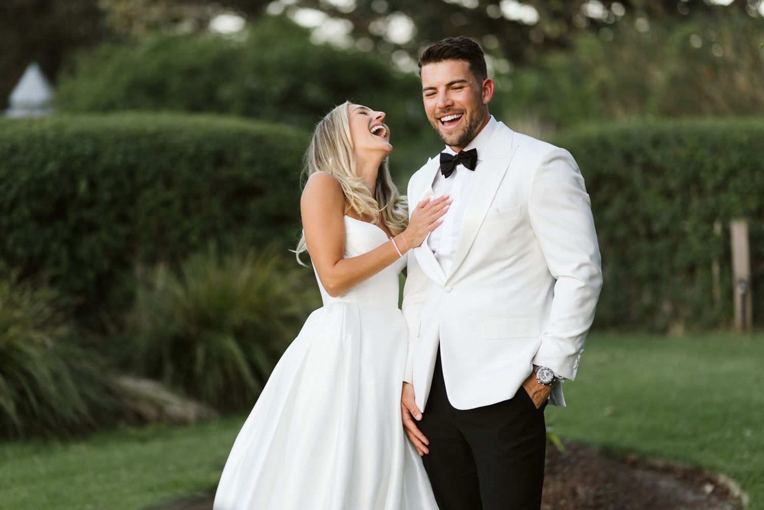 Candid moment of couple laughing in formal wedding attire.