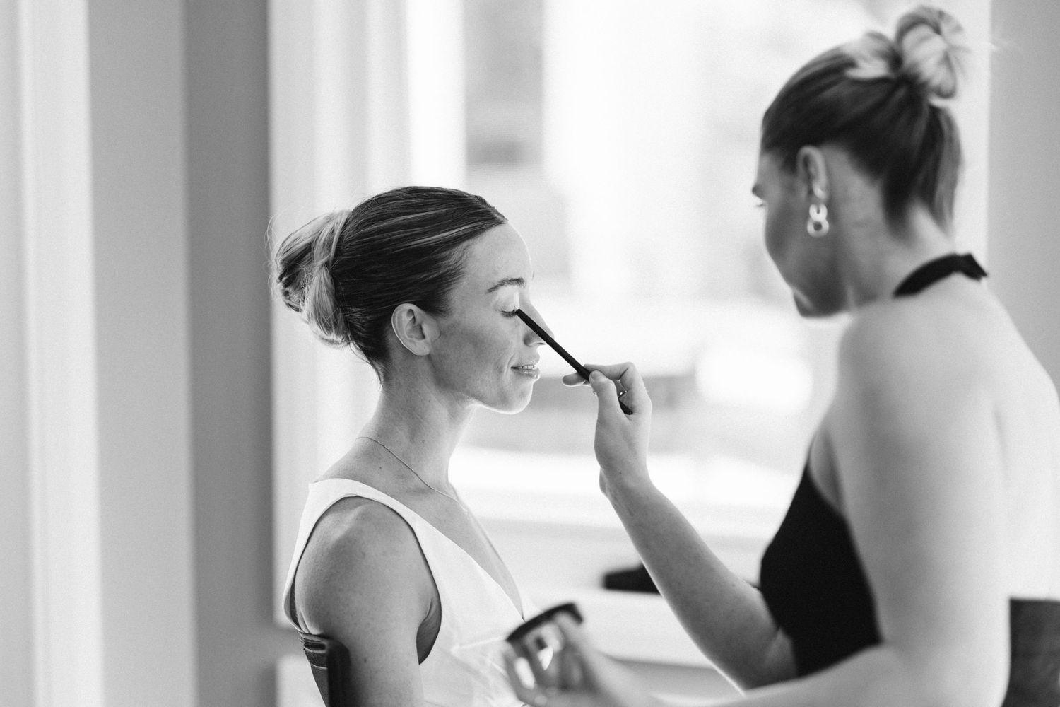 Black and white photo of wedding day makeup application in progress.