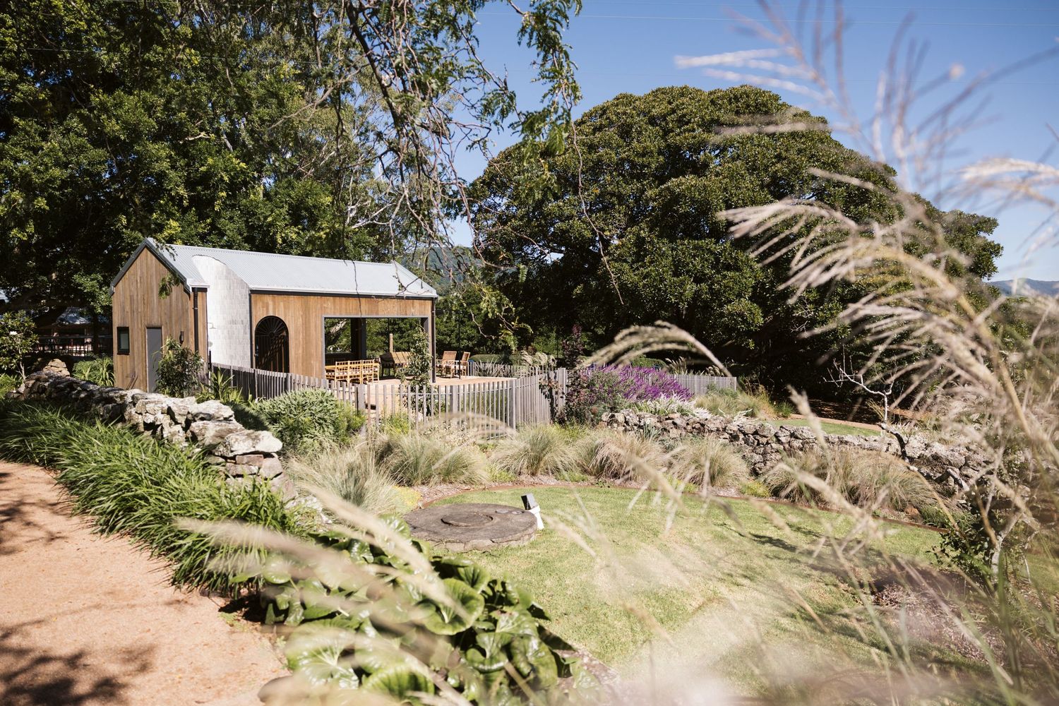 A rustic garden cottage surrounded by ornamental grasses and native landscaping.