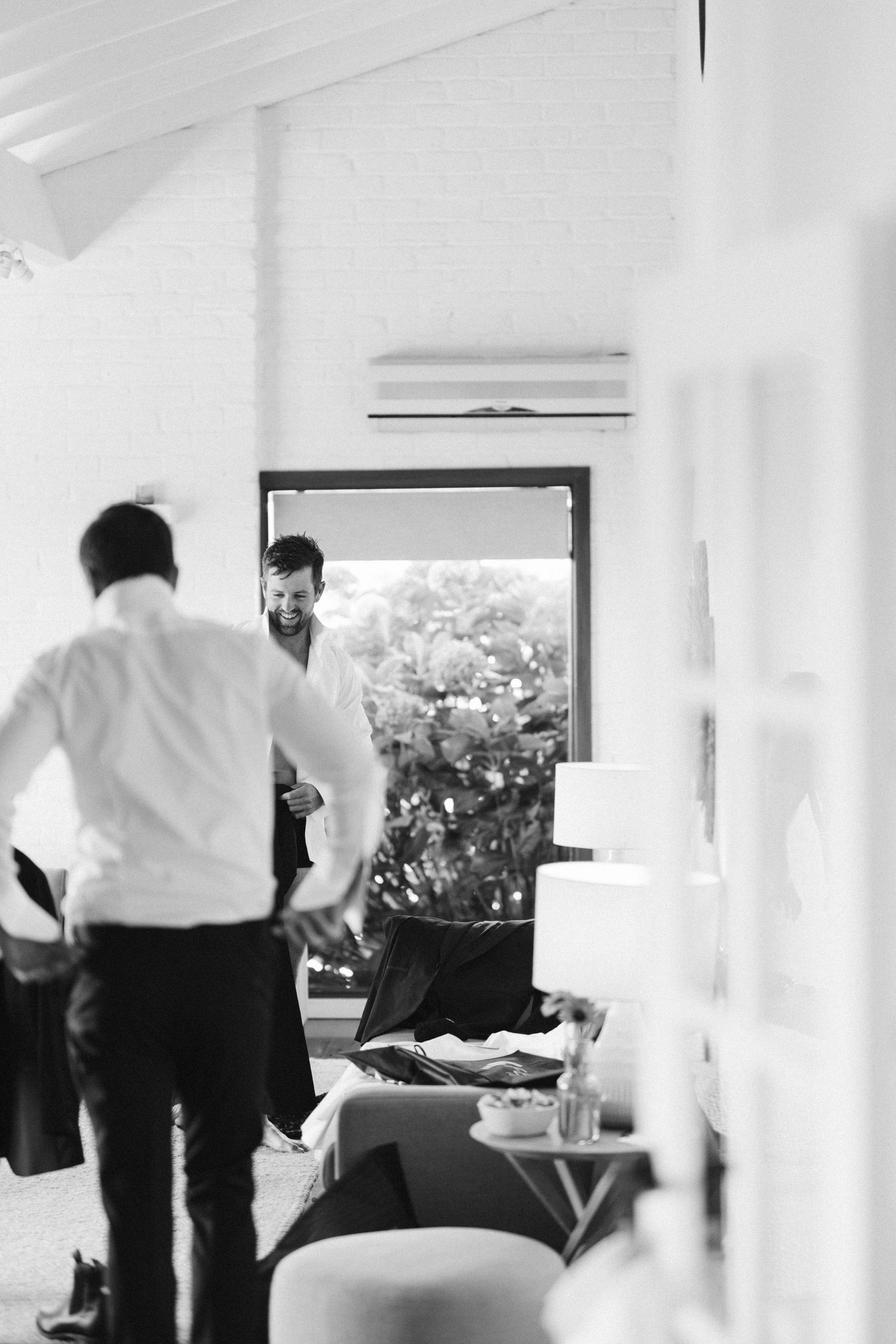 Interior room with bright window and people preparing for formal event.