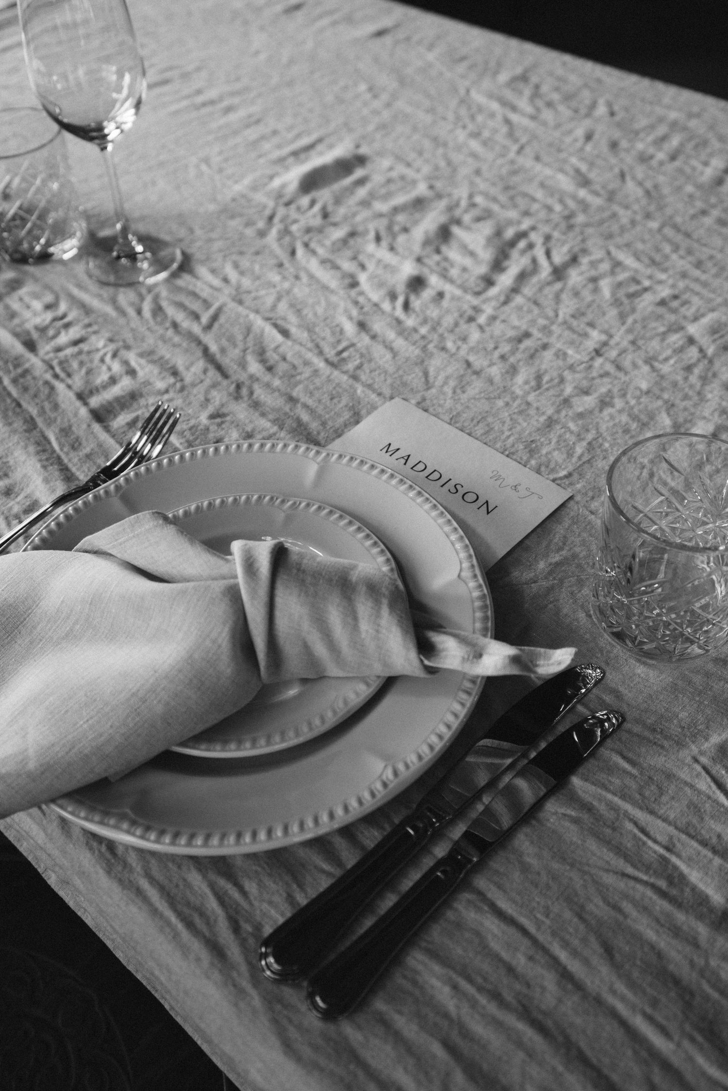 Black and white detail of place setting with folded napkin and menu card.