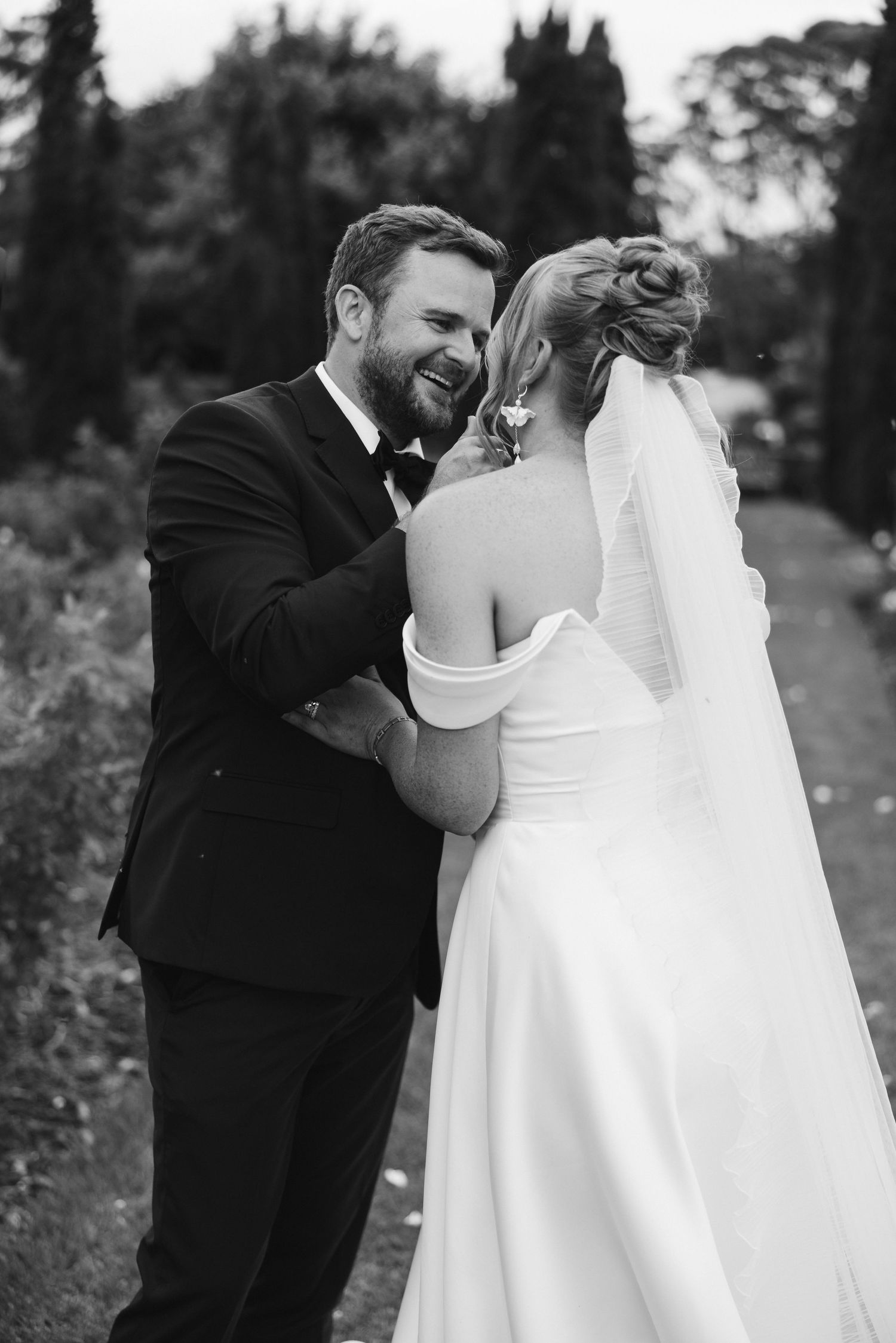 Black and white candid moment of joyful laughter between newlyweds.