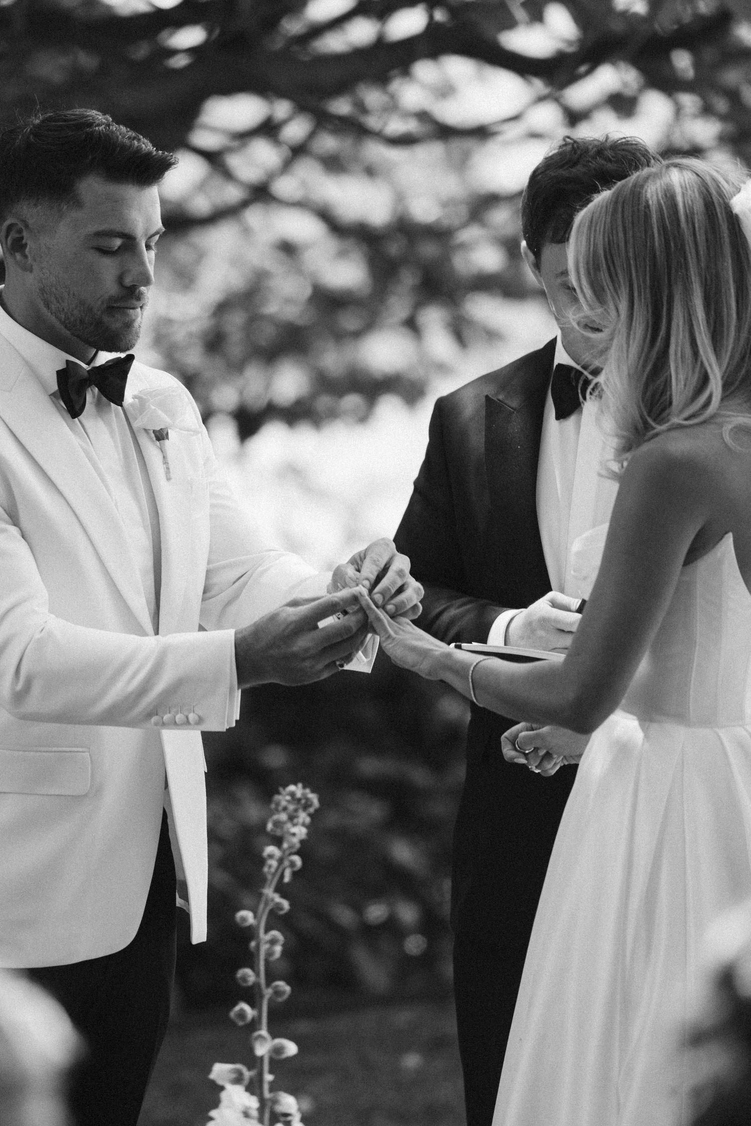 Intimate moment during ring exchange at outdoor wedding ceremony.