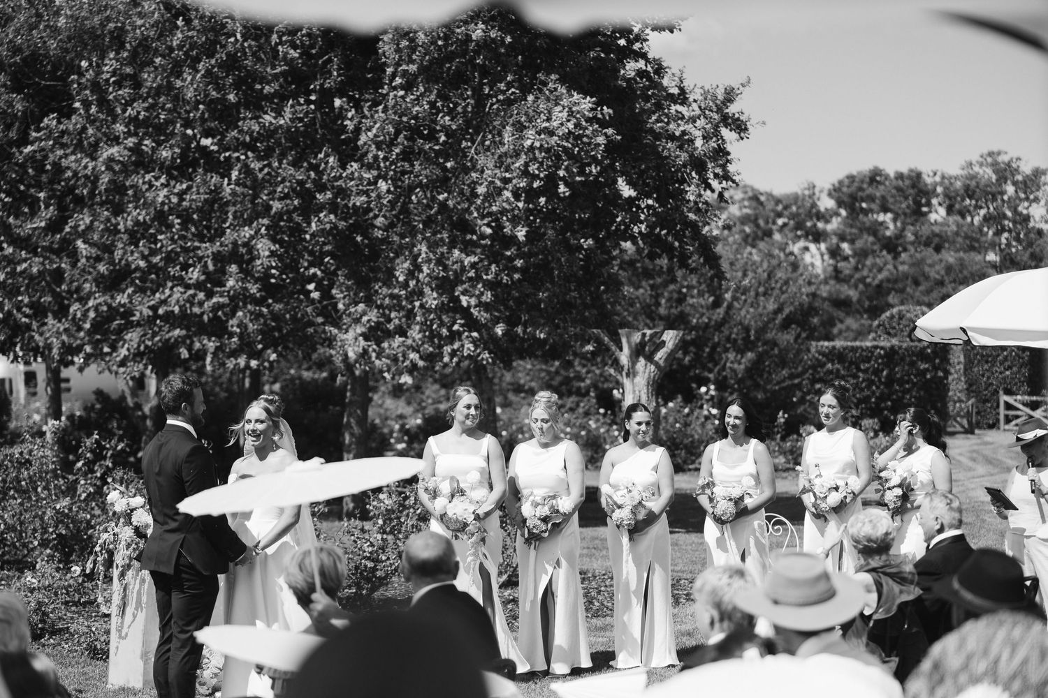 A black and white photograph of a wedding celebration with attendees in the garden.