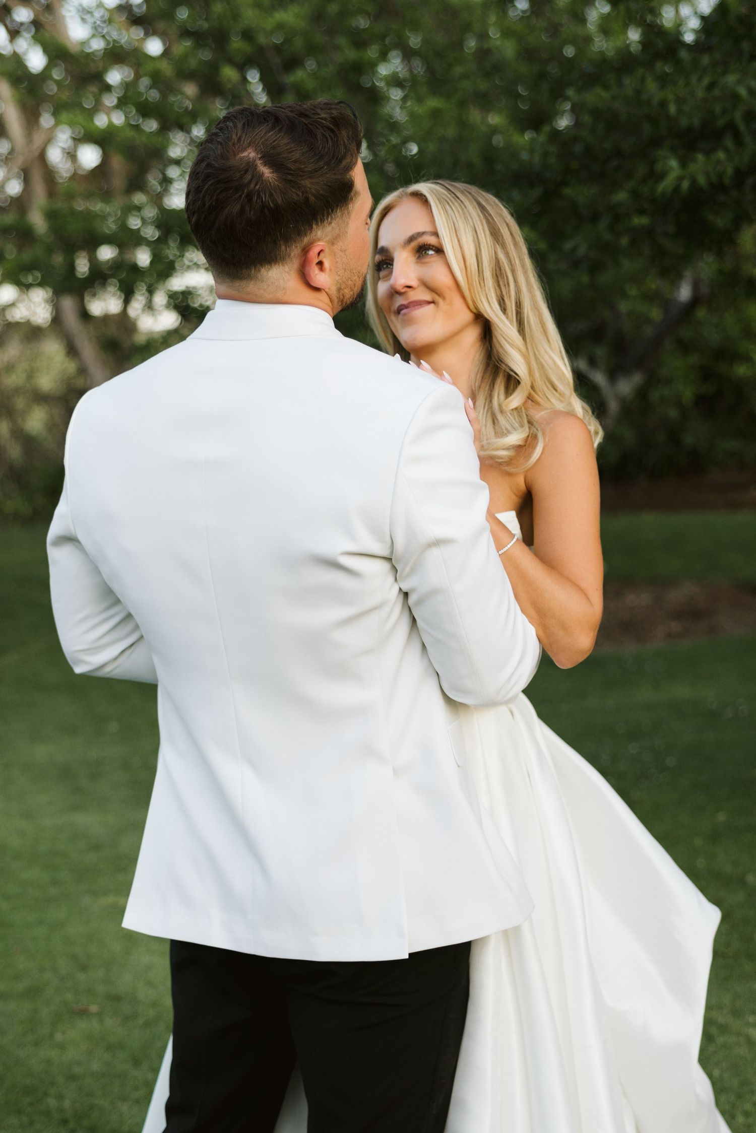 Romantic outdoor portrait of newlyweds in elegant white wedding attire.