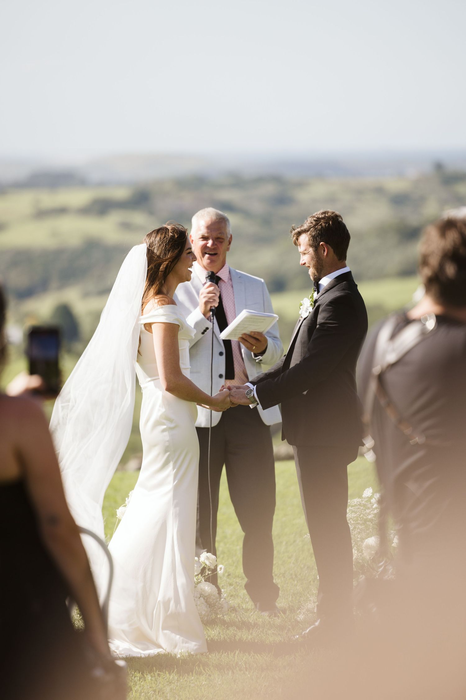 Intimate outdoor wedding ceremony on a hillside with scenic valley views in the background.