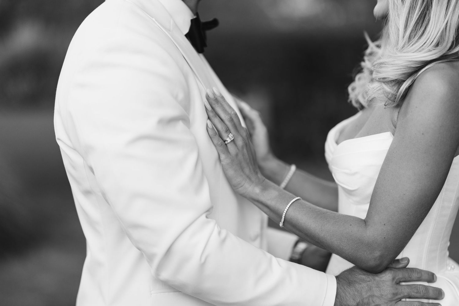 Close-up shot of newlyweds embracing in formal black and white wedding attire.