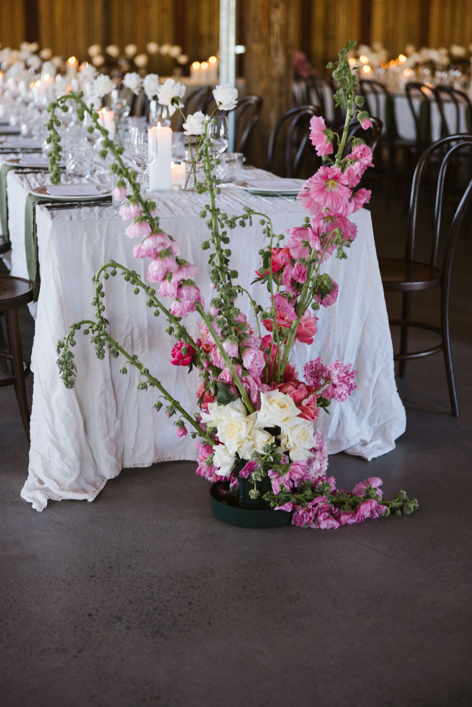 Pink and white floral centerpiece with tall snapdragons on an elegant white tablecloth.