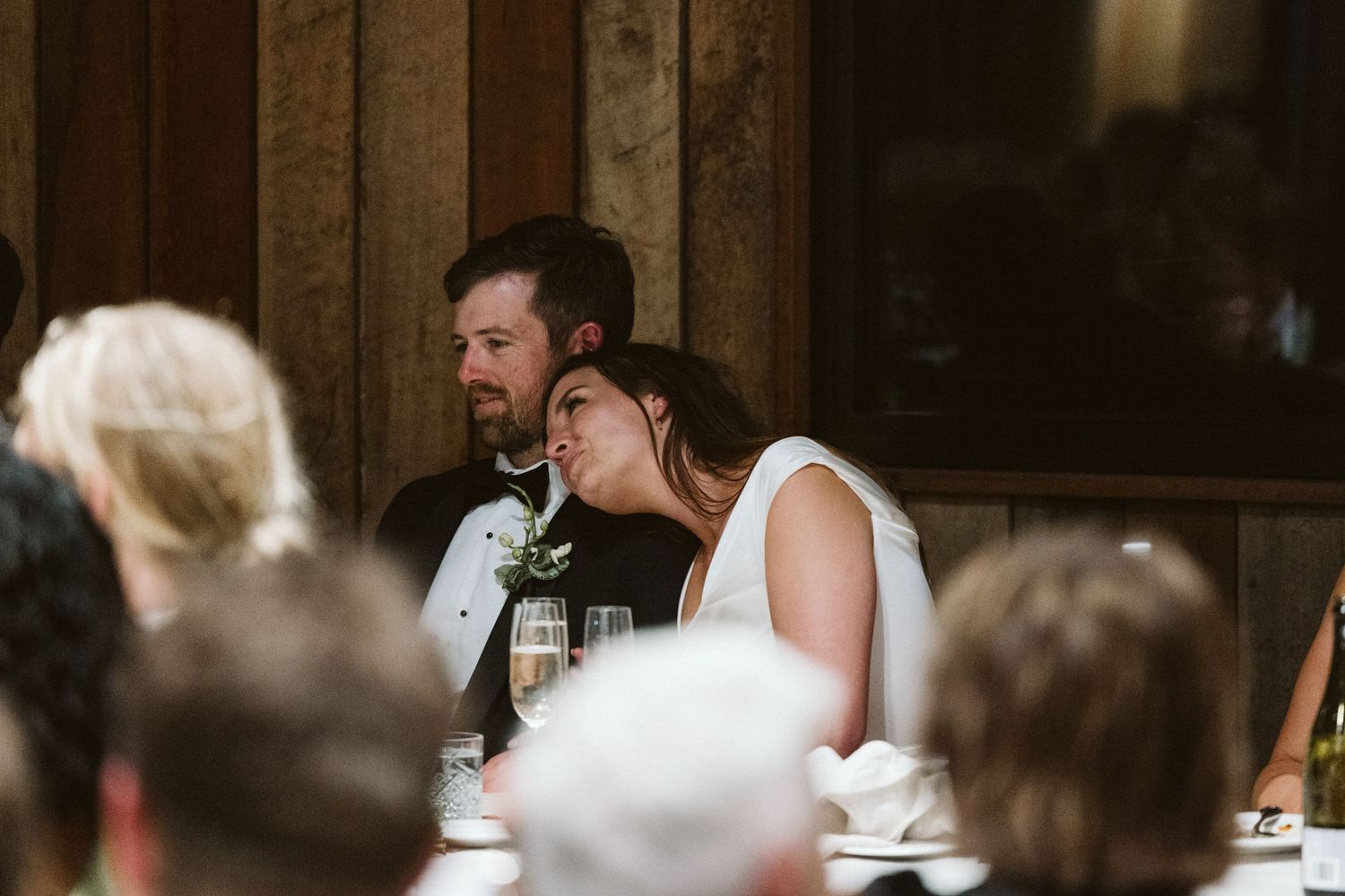 Emotional moment captured during wedding reception toasts in rustic venue.