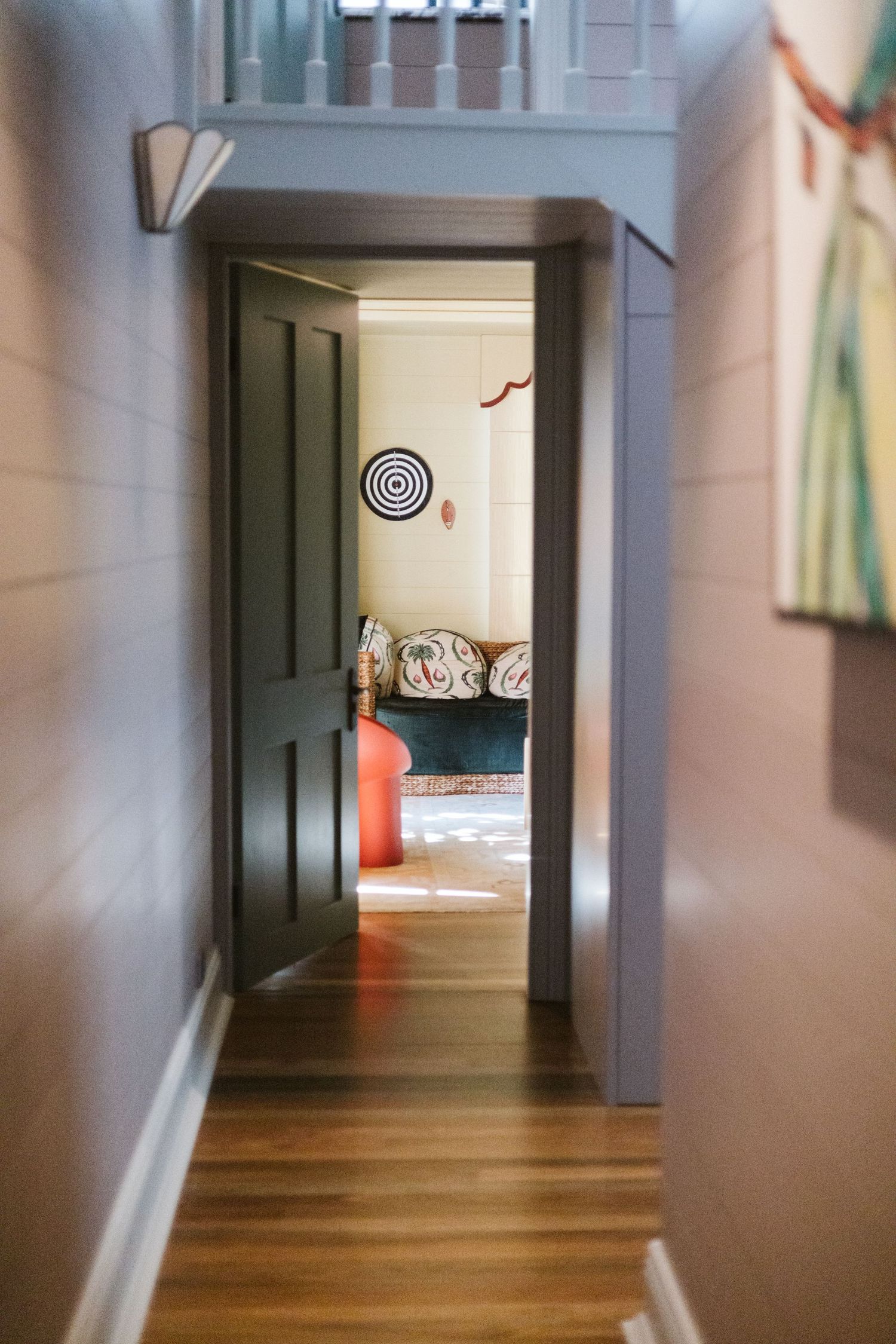 Hallway with hardwood floors leads to a cozy room with circular wall art.