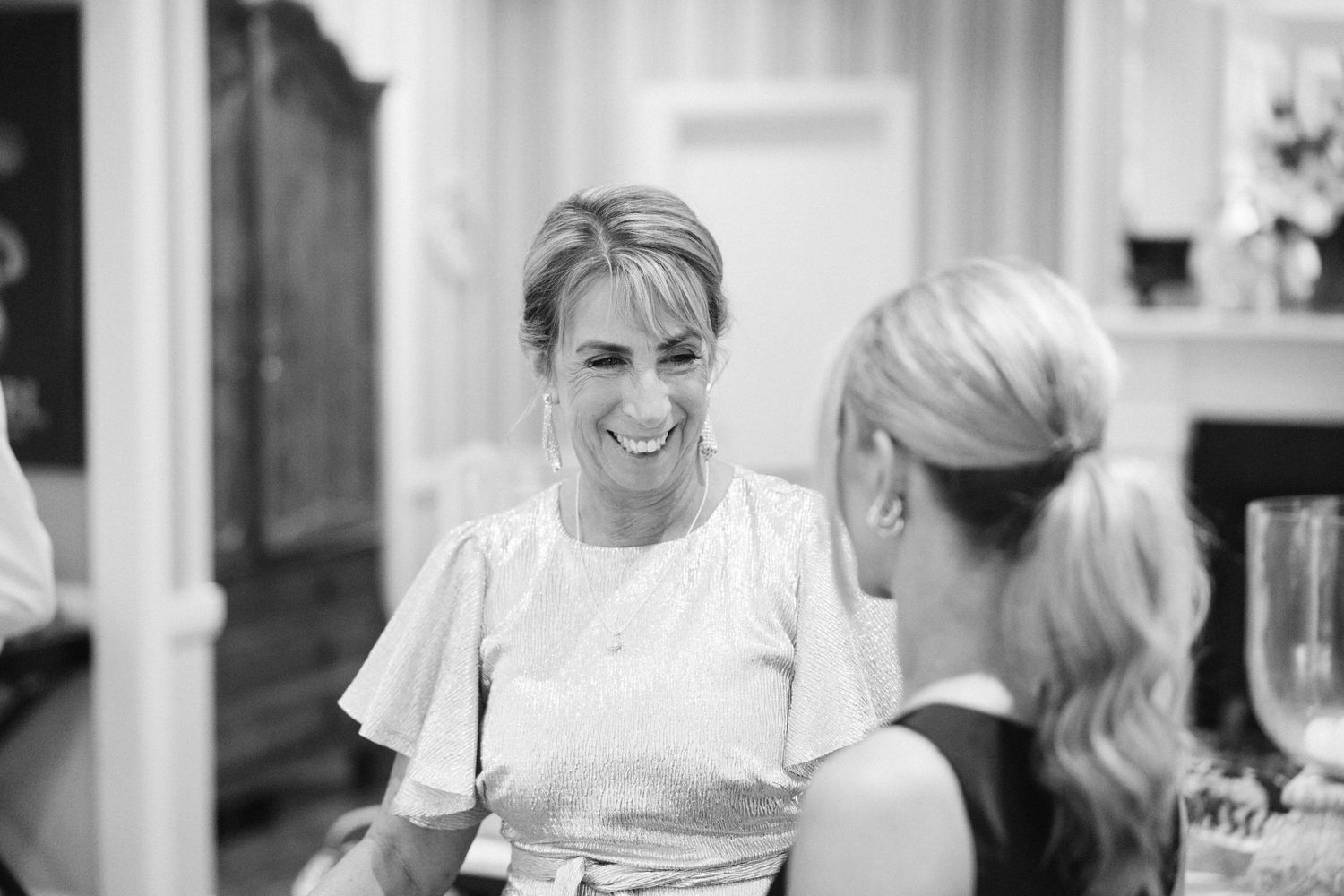 Two women sharing a joyful conversation at a gathering.