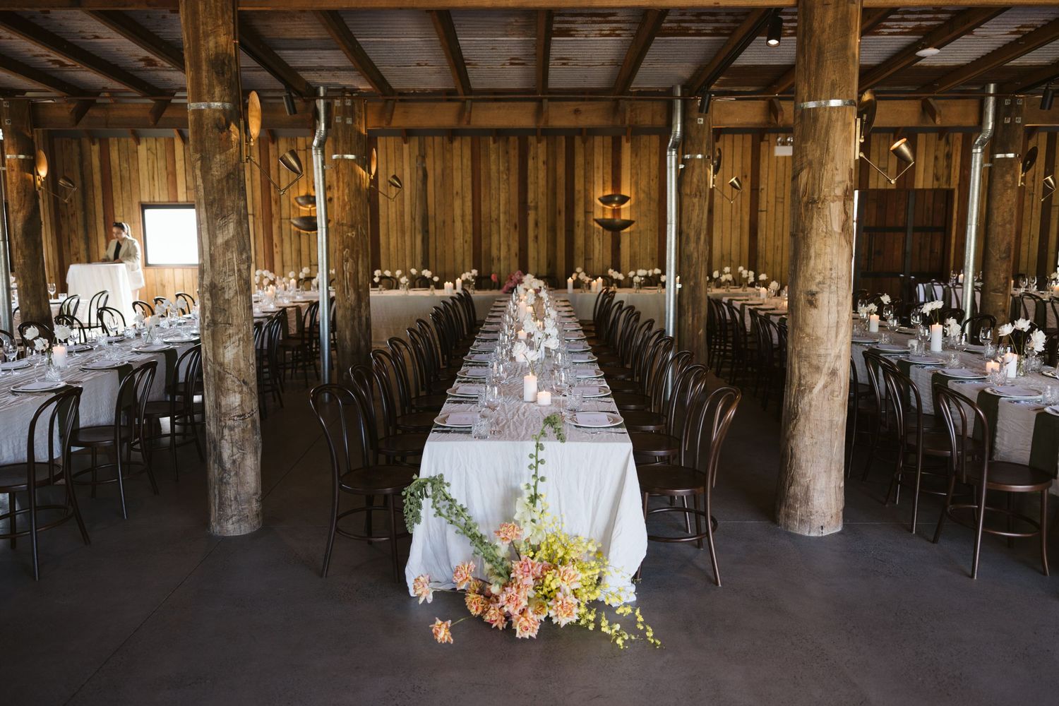 Rustic barn wedding reception setup with long tables and exposed wooden beams.