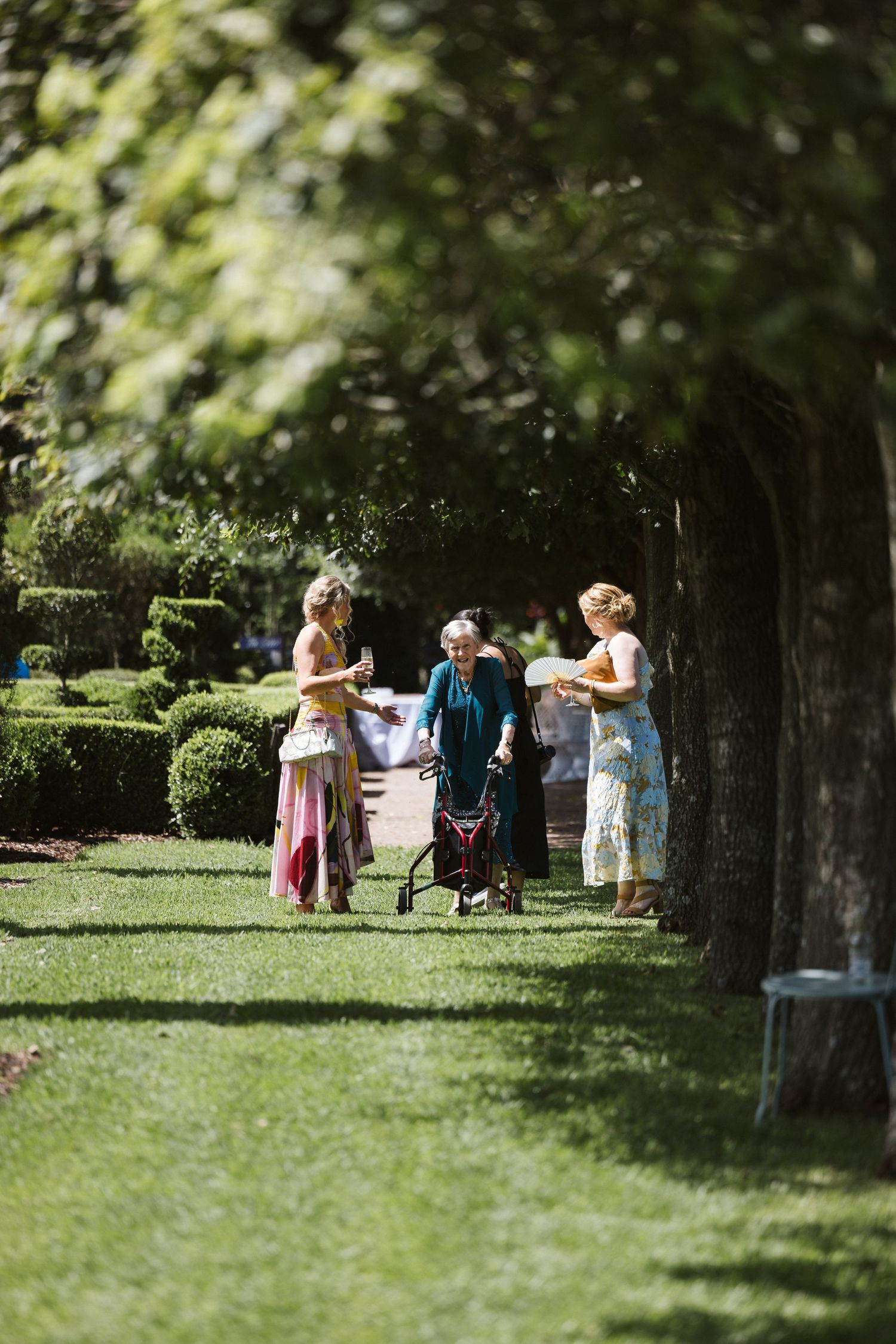 Small group chatting while walking along shaded garden path.
