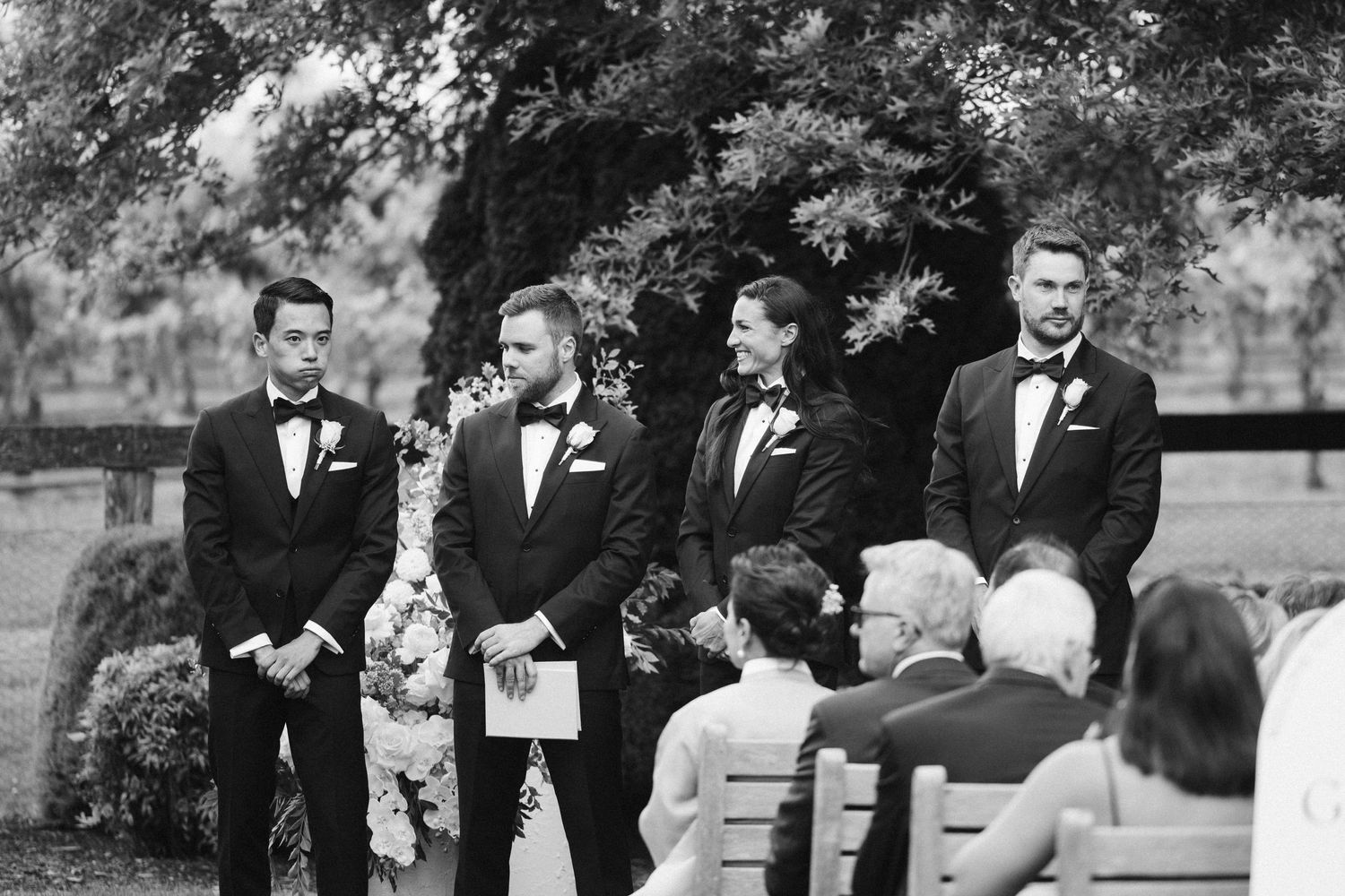 Black and white photo of wedding ceremony with guests seated outdoors.