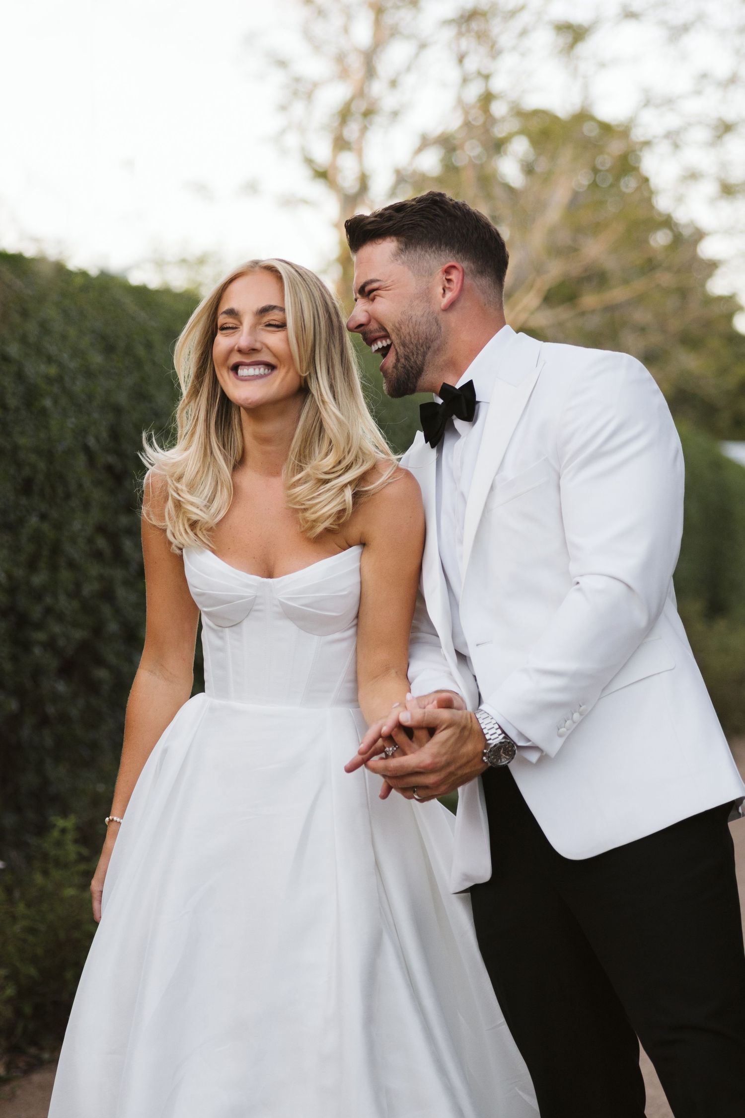 Joyful couple sharing candid laughter in formal wedding attire.