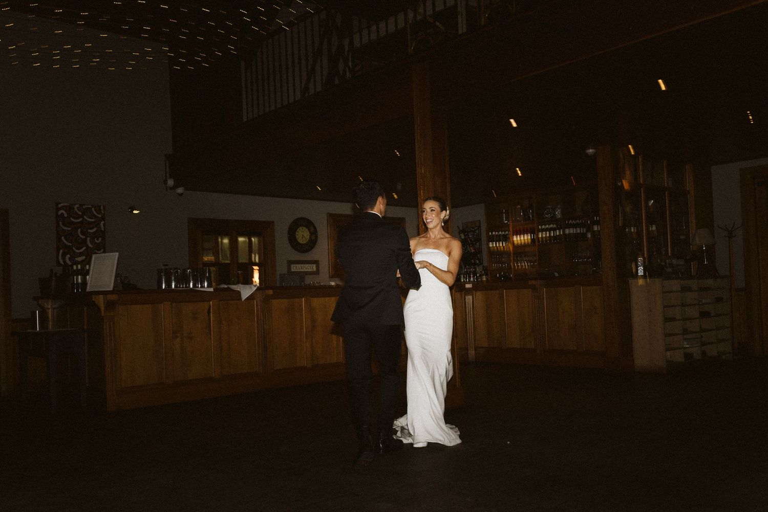 A couple slow dances in an intimate moment at their wedding reception in a dimly lit venue.