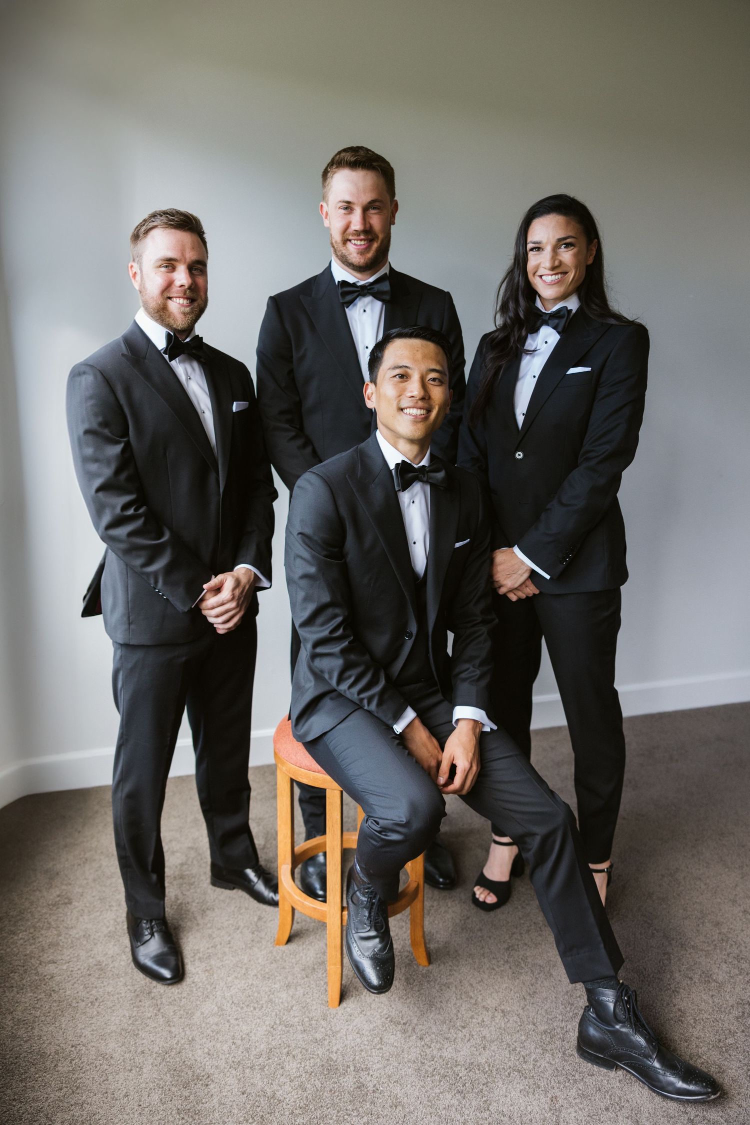 A wedding party of four people in formal attire poses together for a portrait.