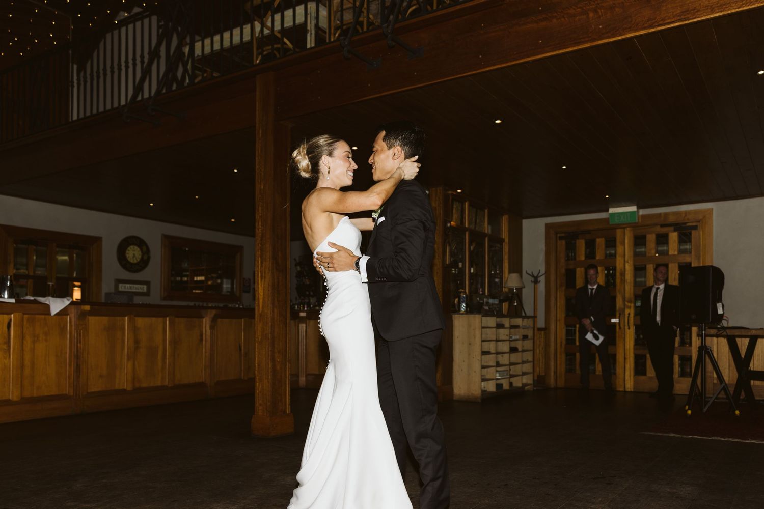 A couple shares a joyful dance moment during their wedding reception under twinkling lights.