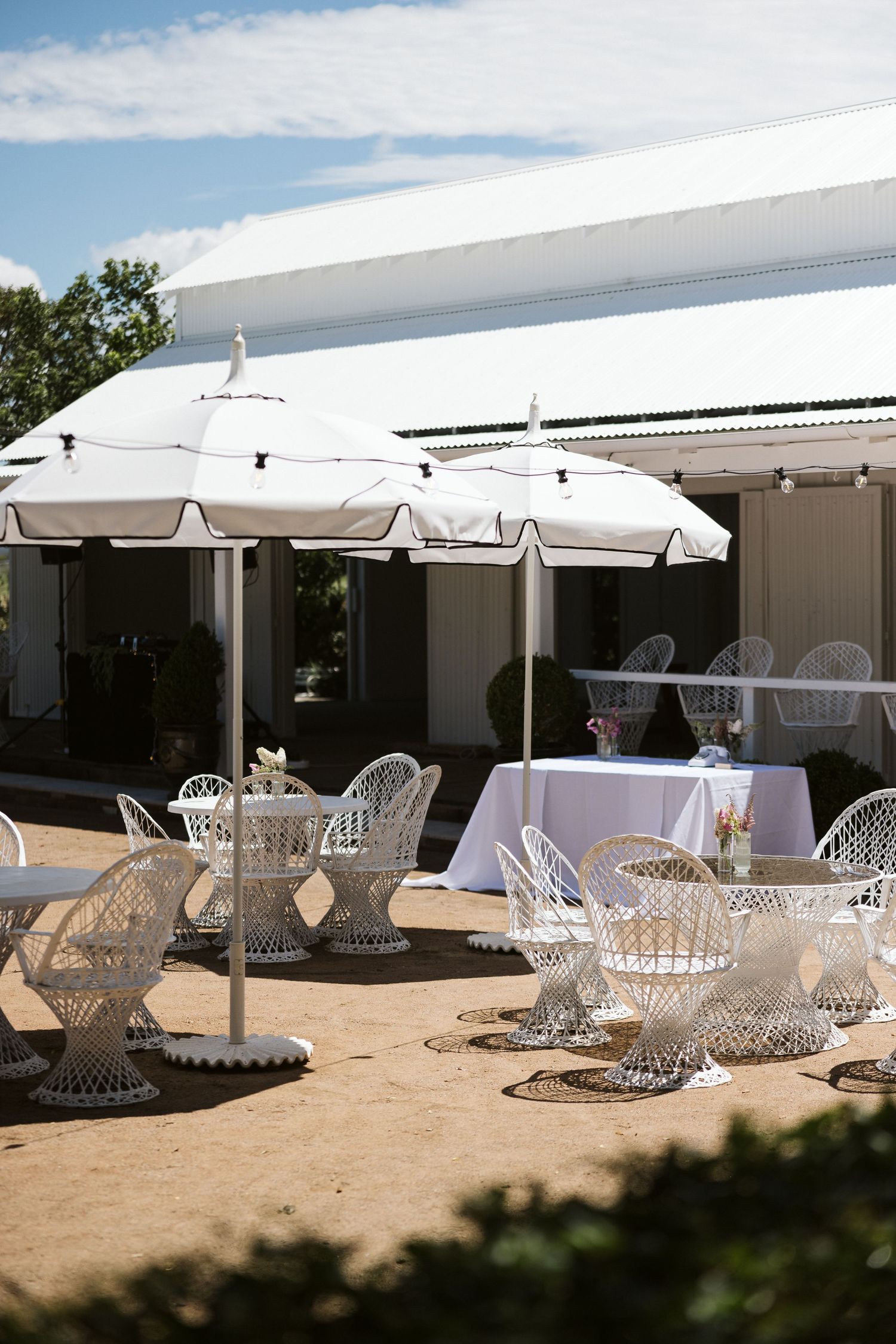 Outdoor dining area with white parasols and ornate crystal glassware on tables.