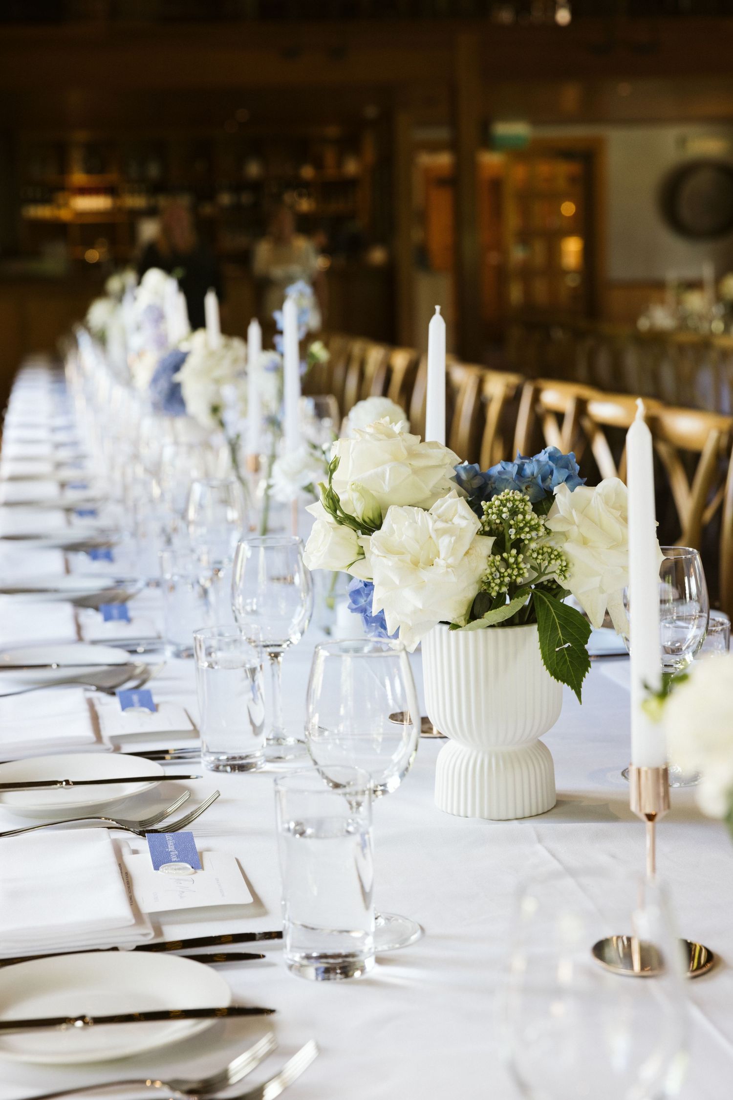 An elegant table setting with white and blue floral centerpieces and crystal glassware.