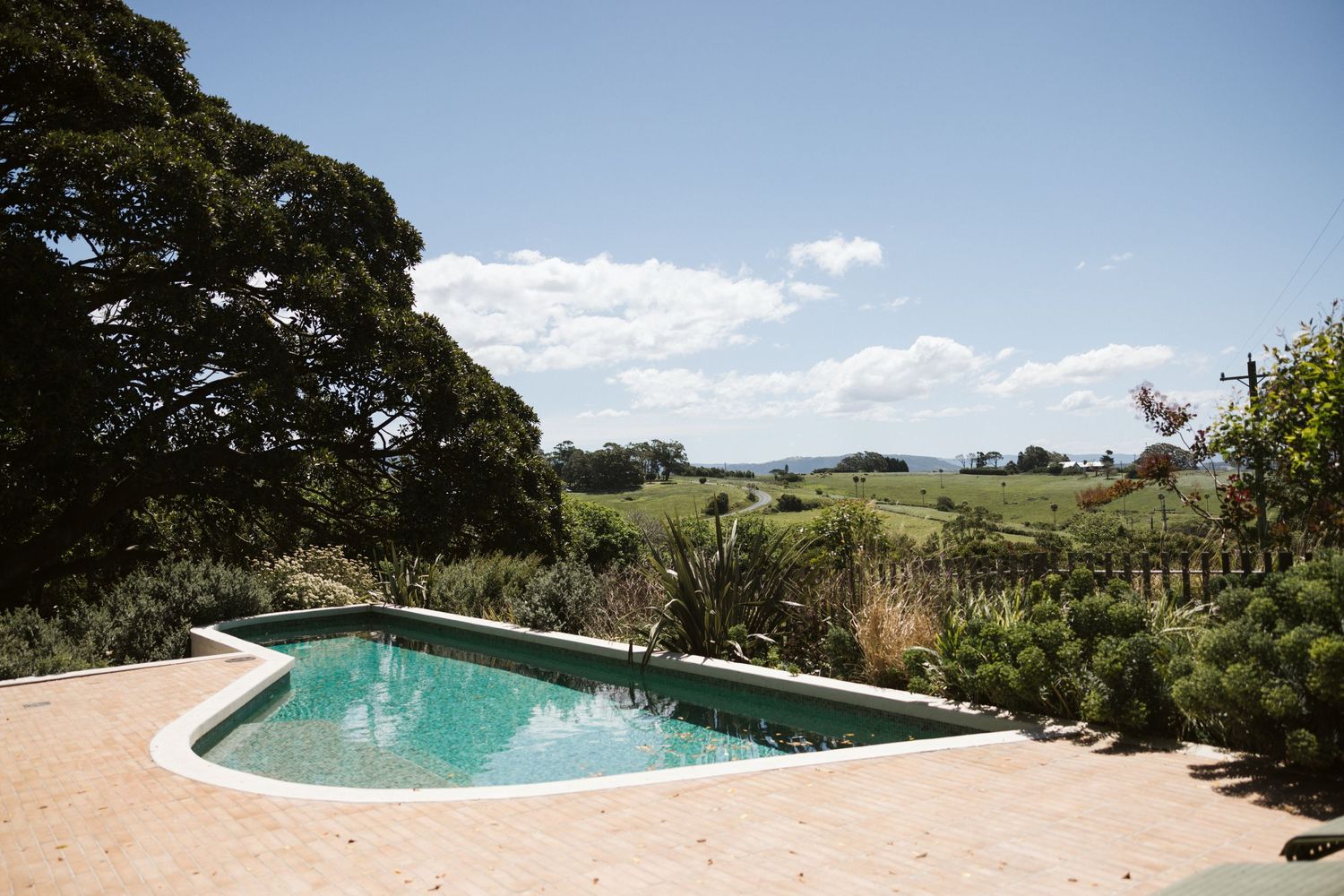 An infinity pool overlooks rolling hills and pastoral countryside on a sunny day.