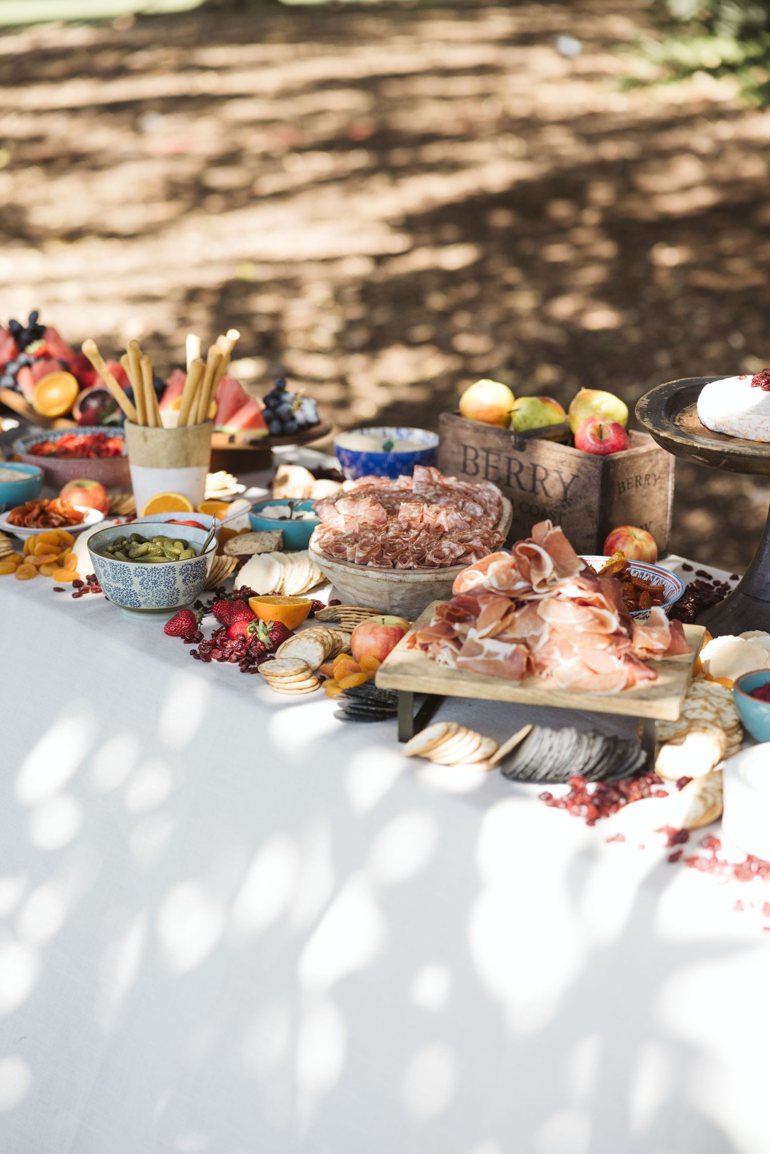 An elegant charcuterie spread with meats, cheeses, and fruits on a white tablecloth.