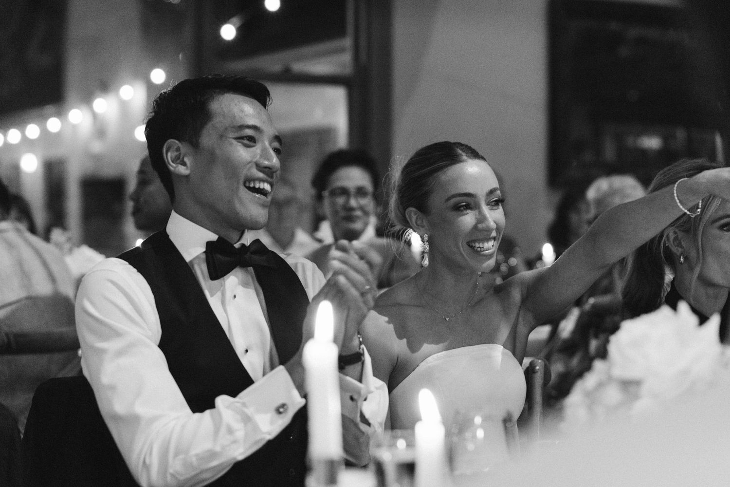 A black and white photo of a couple sharing a joyful moment at their wedding reception.
