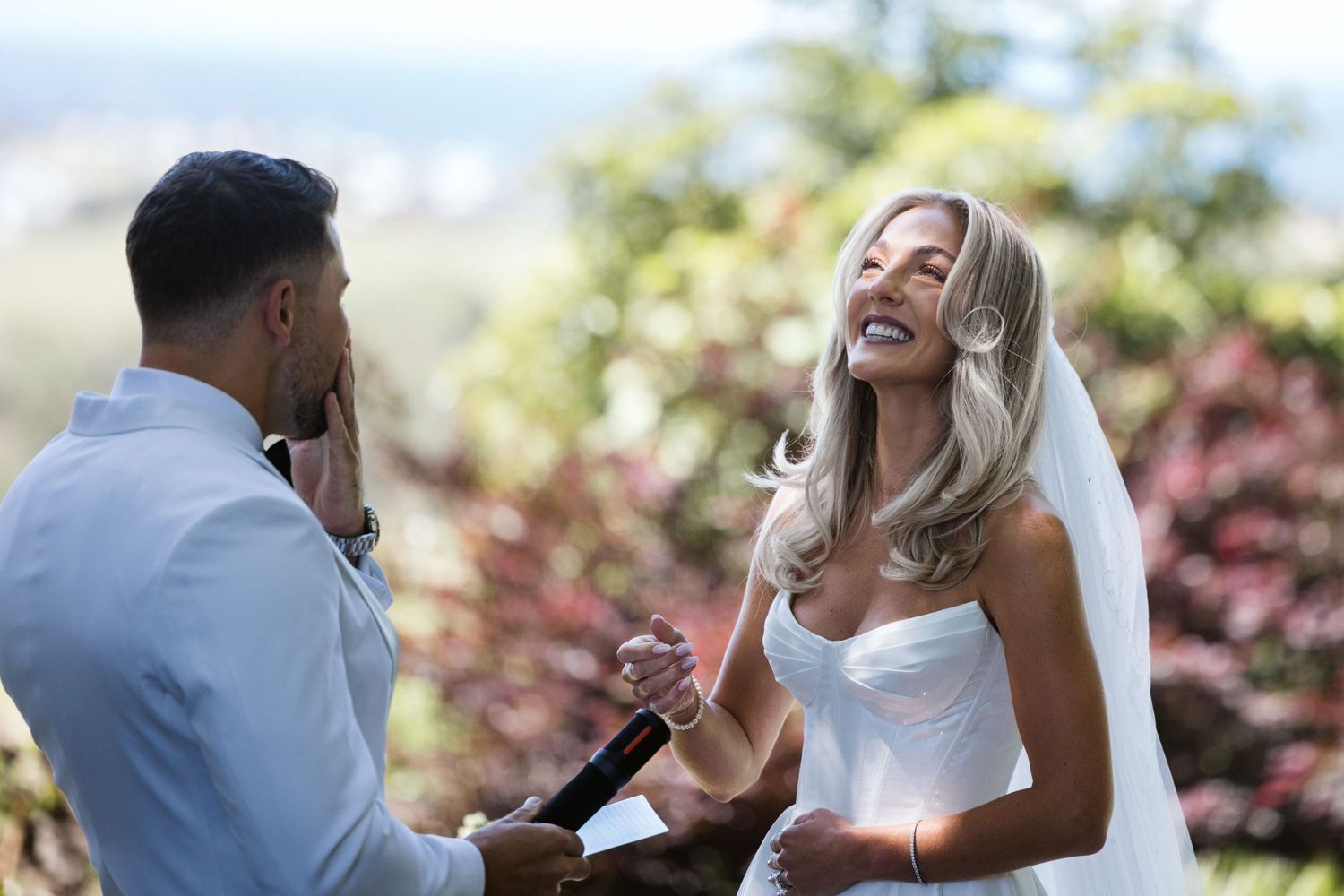 Two people share an emotional moment during wedding vows in a garden setting.