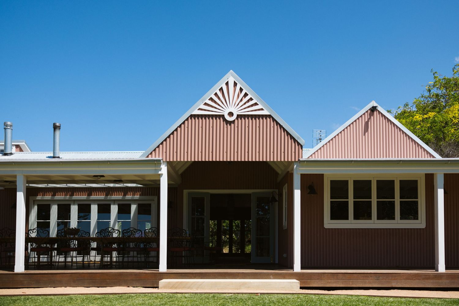 A charming rustic building with peaked roofs and a covered porch against bright blue sky.