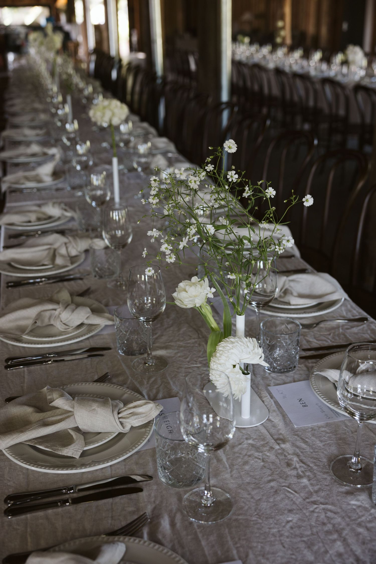 Elegant table setting with white floral centerpieces and crystal glassware at a formal reception.