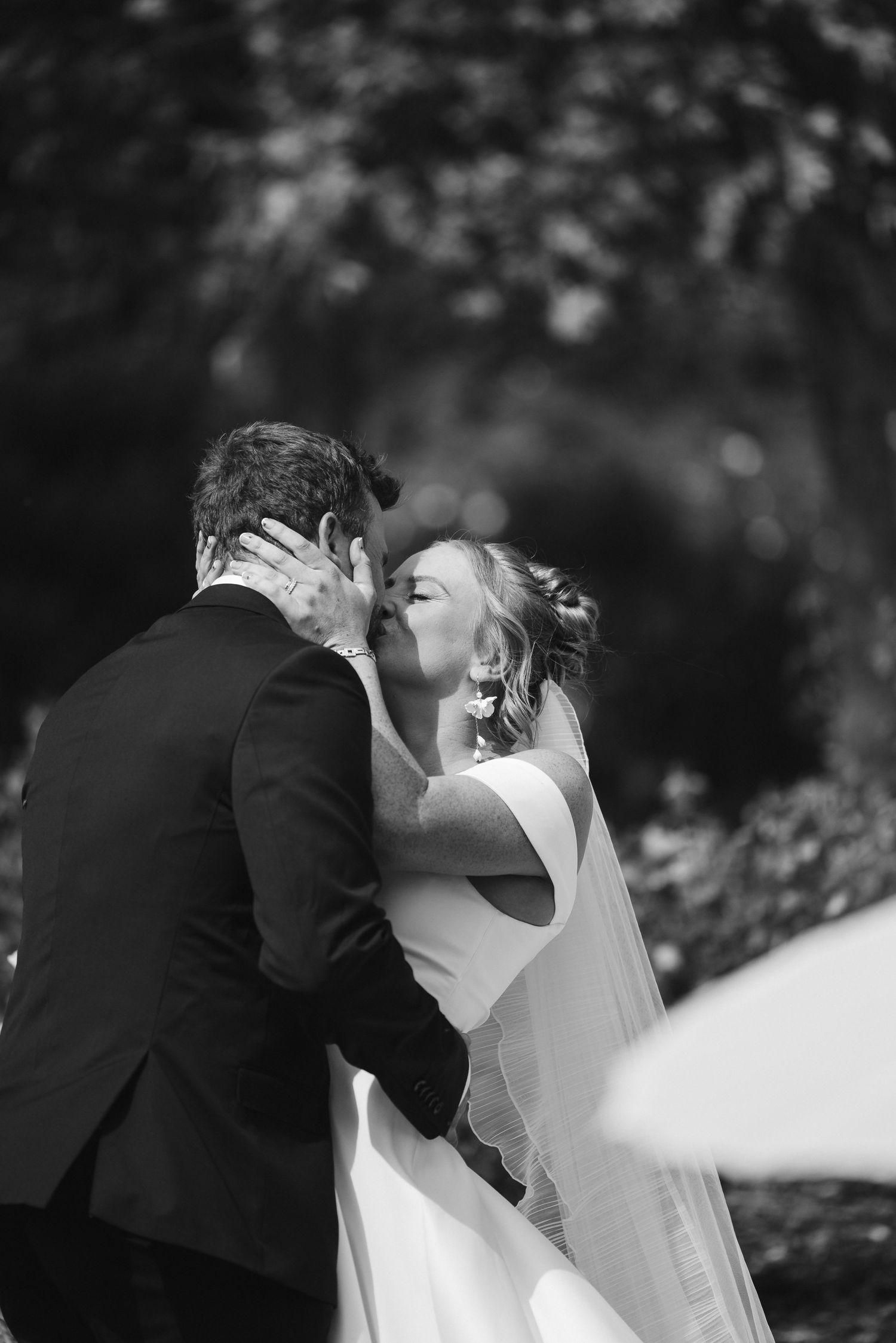 Intimate black and white portrait of newlyweds sharing their first kiss.