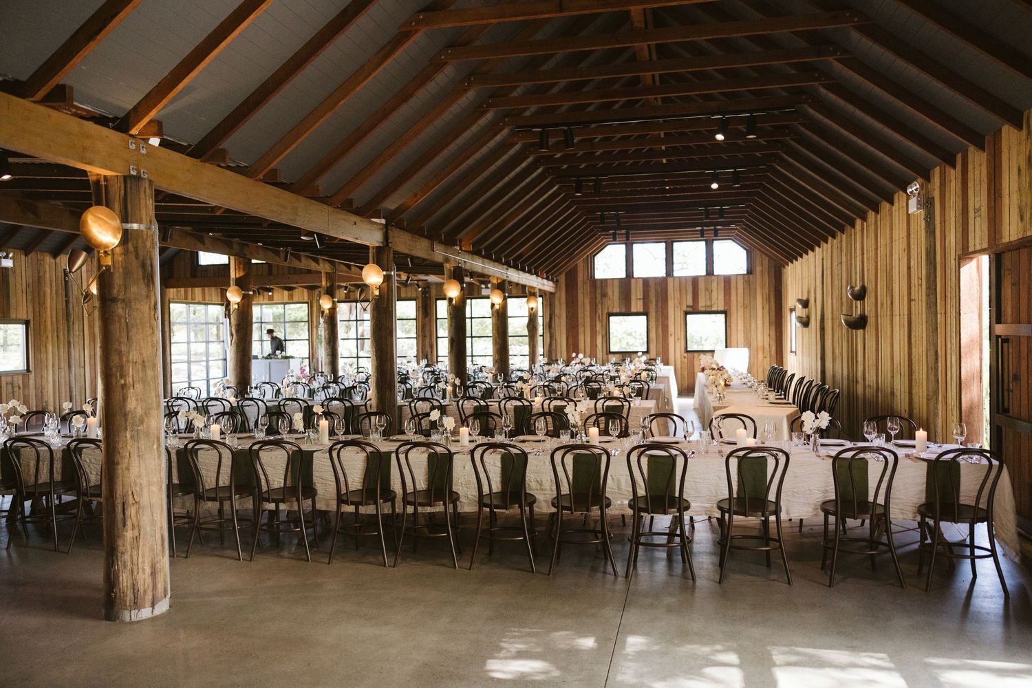 Rustic wooden wedding venue with vaulted ceiling and rows of black chairs set for reception.